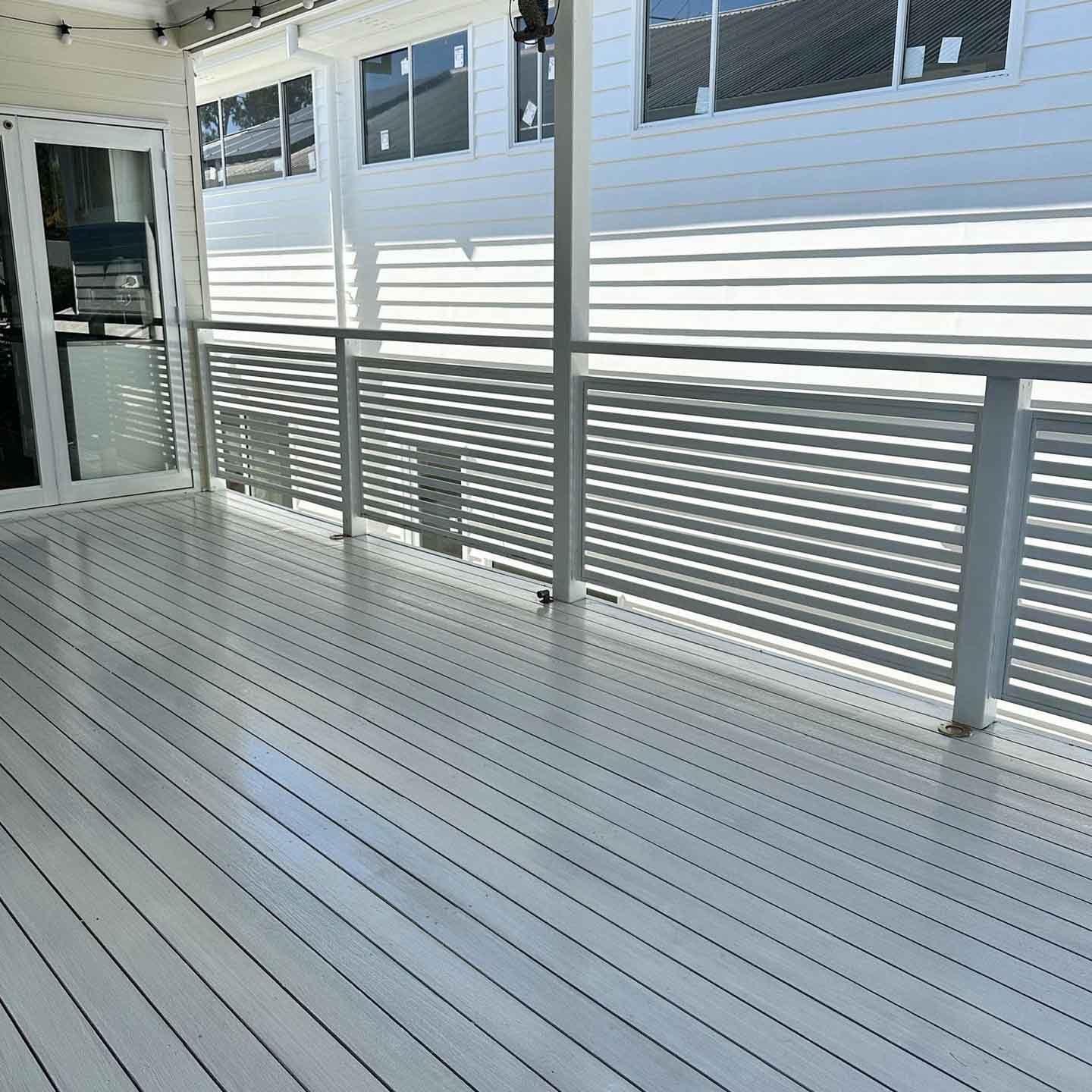 Pale grey coated deck with white slatted balustrade on a weatherboard house