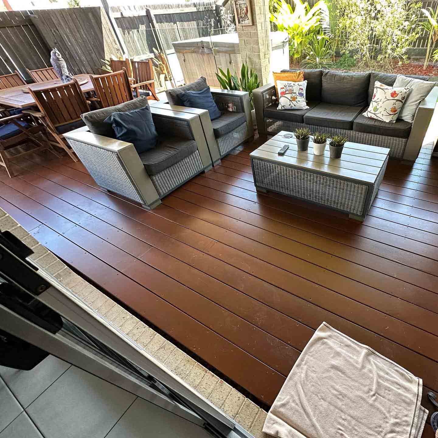 Oiled timber deck with a wicker outdoor lounge suite and coffee table