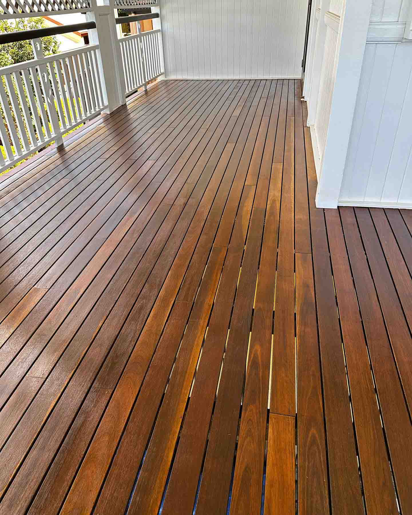 Oiled timber verandah with white timber balustrade along a white house