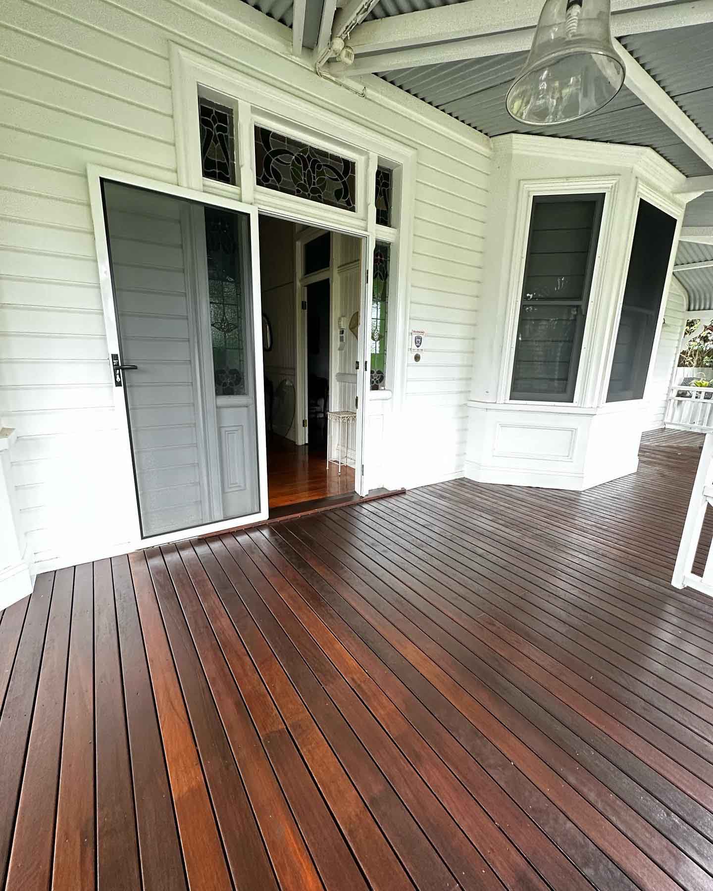 Oiled timber verandah outside a white weatherboard house's front door