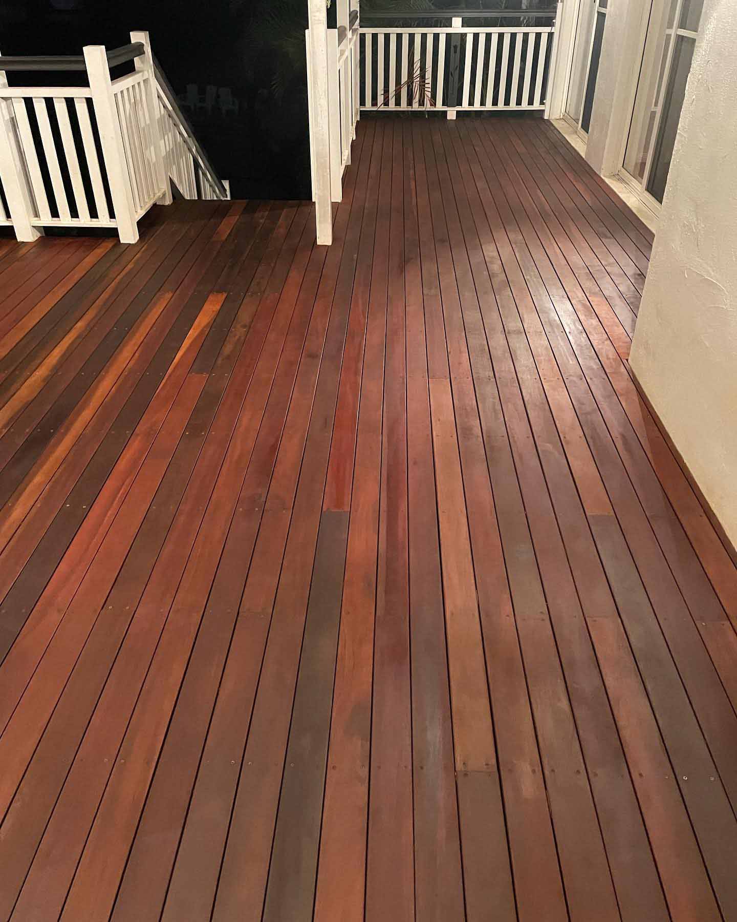 Long dark oiled timber verandah leading to white timber stairs