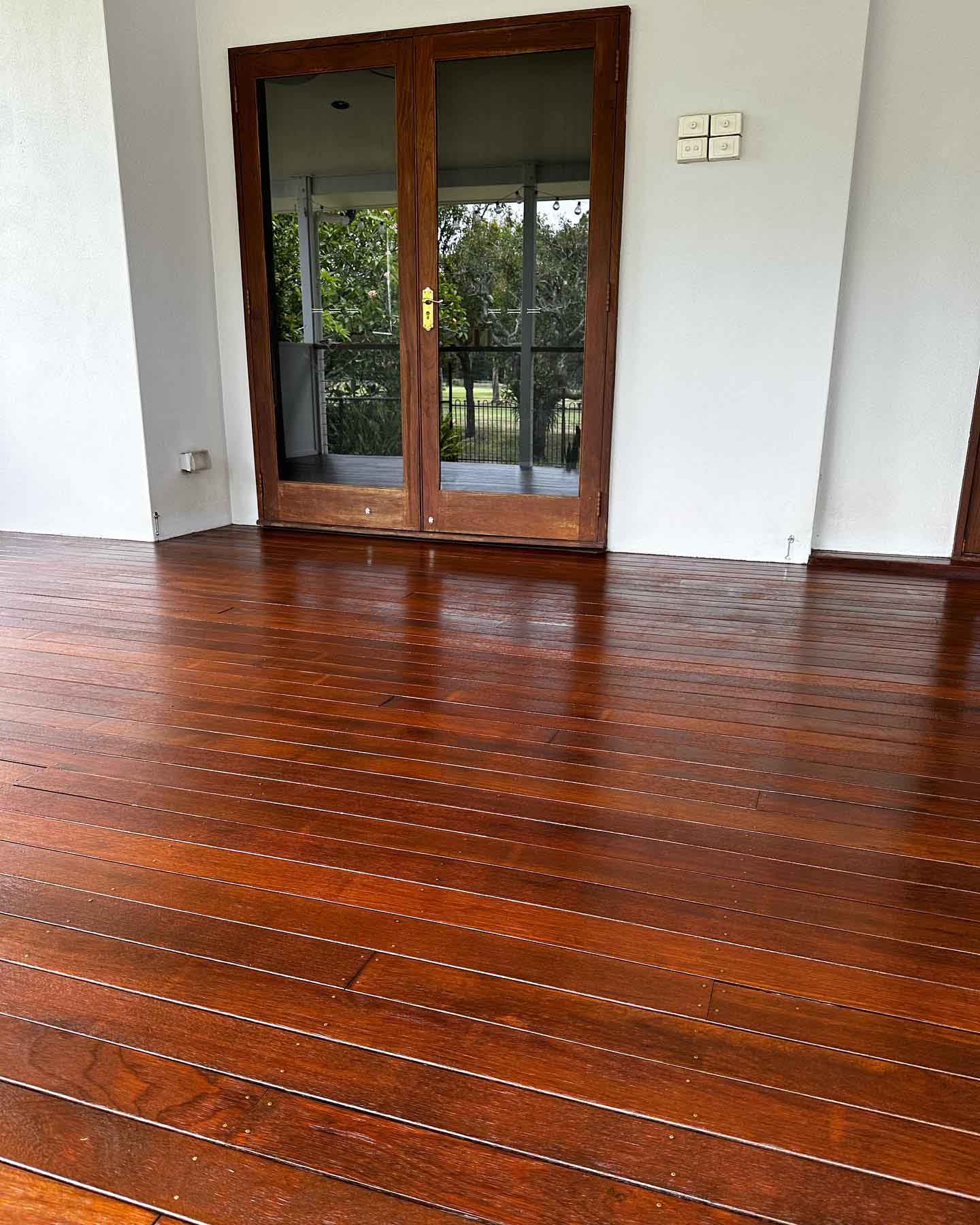 Glossy oiled timber deck in front of timber French doors