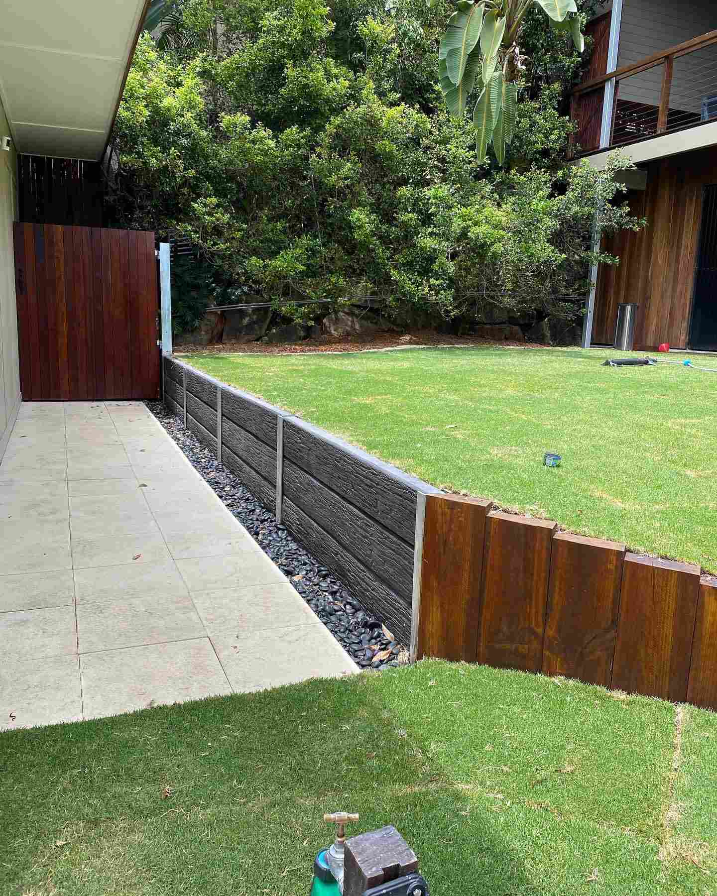 Timber sleeper retaining wall and timber gate beside a lawn and path