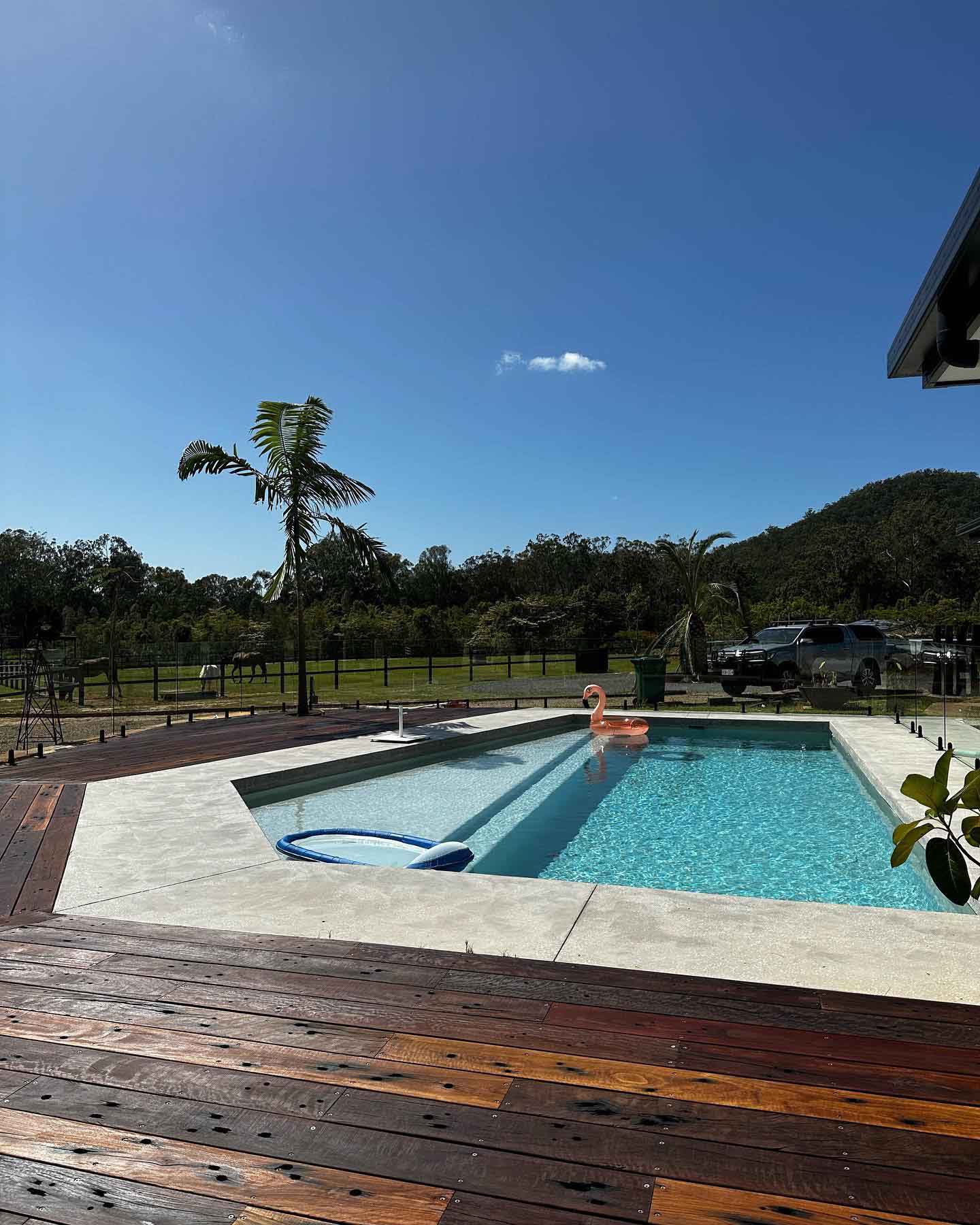 Timber deck beside a rectangular pool with a hill behind