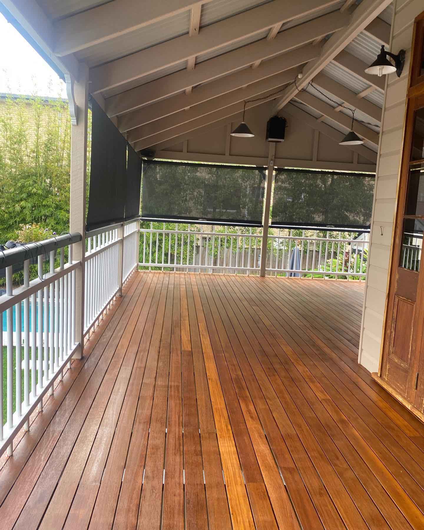 Oiled timber verandah with white balustrade under a raked ceiling and outdoor blinds
