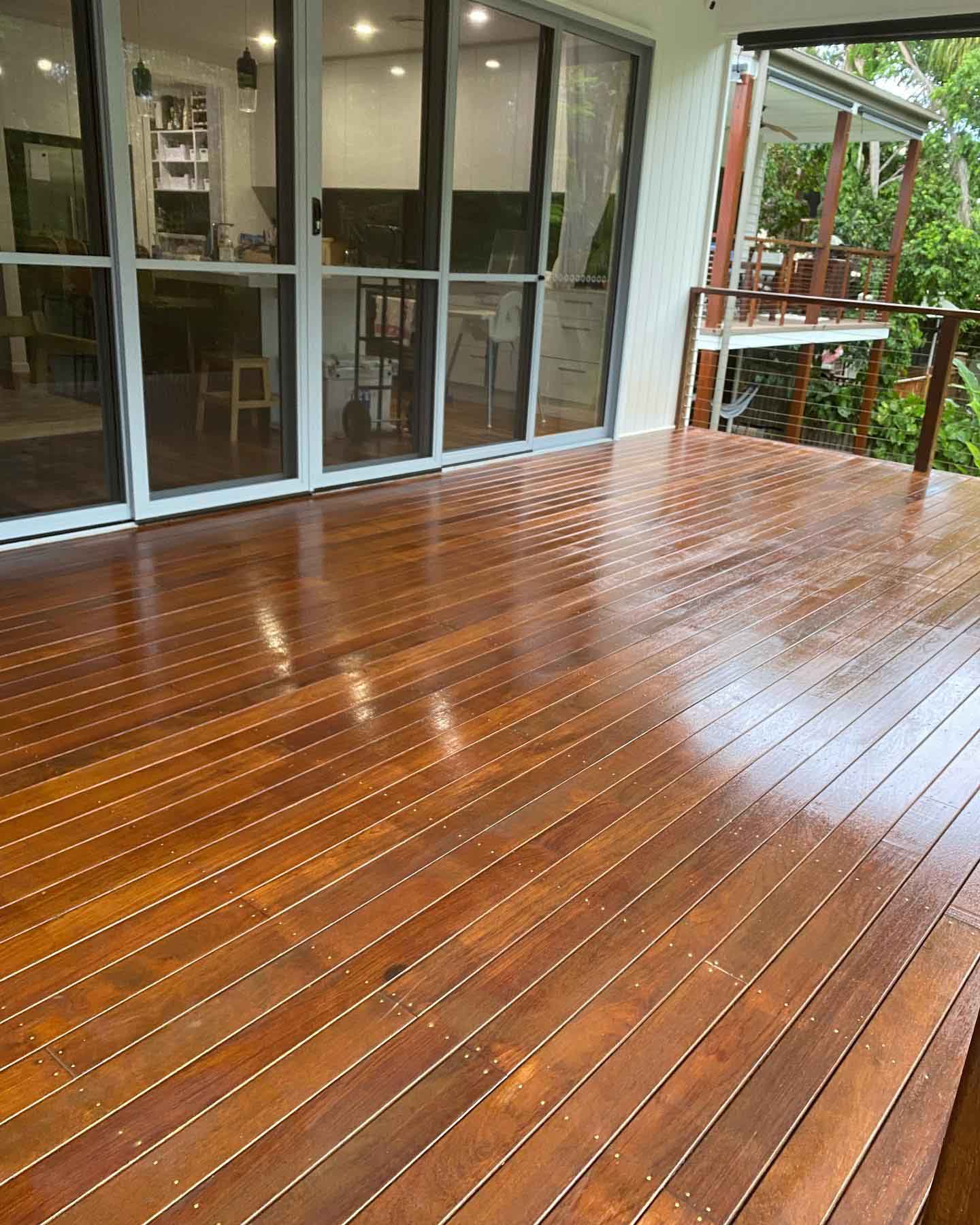 Glossy oiled timber deck outside full-height glass doors