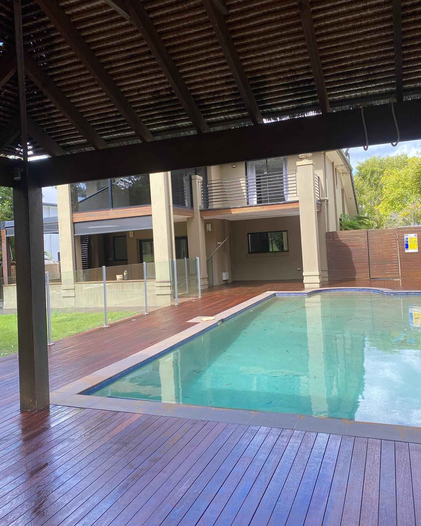 Oiled timber deck around a pool under a timber-raftered roof