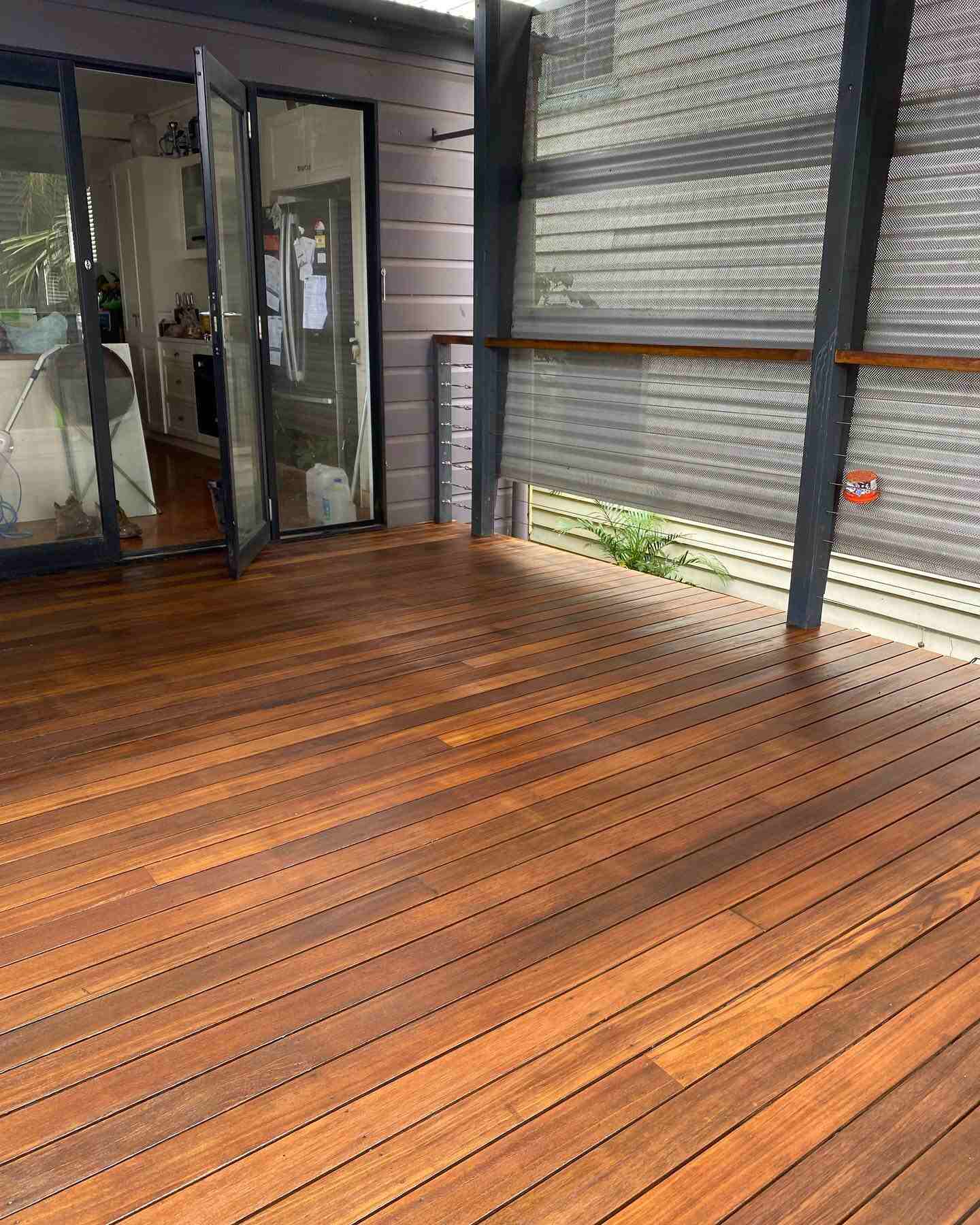 Oiled timber deck outside open glass doors with angled black posts