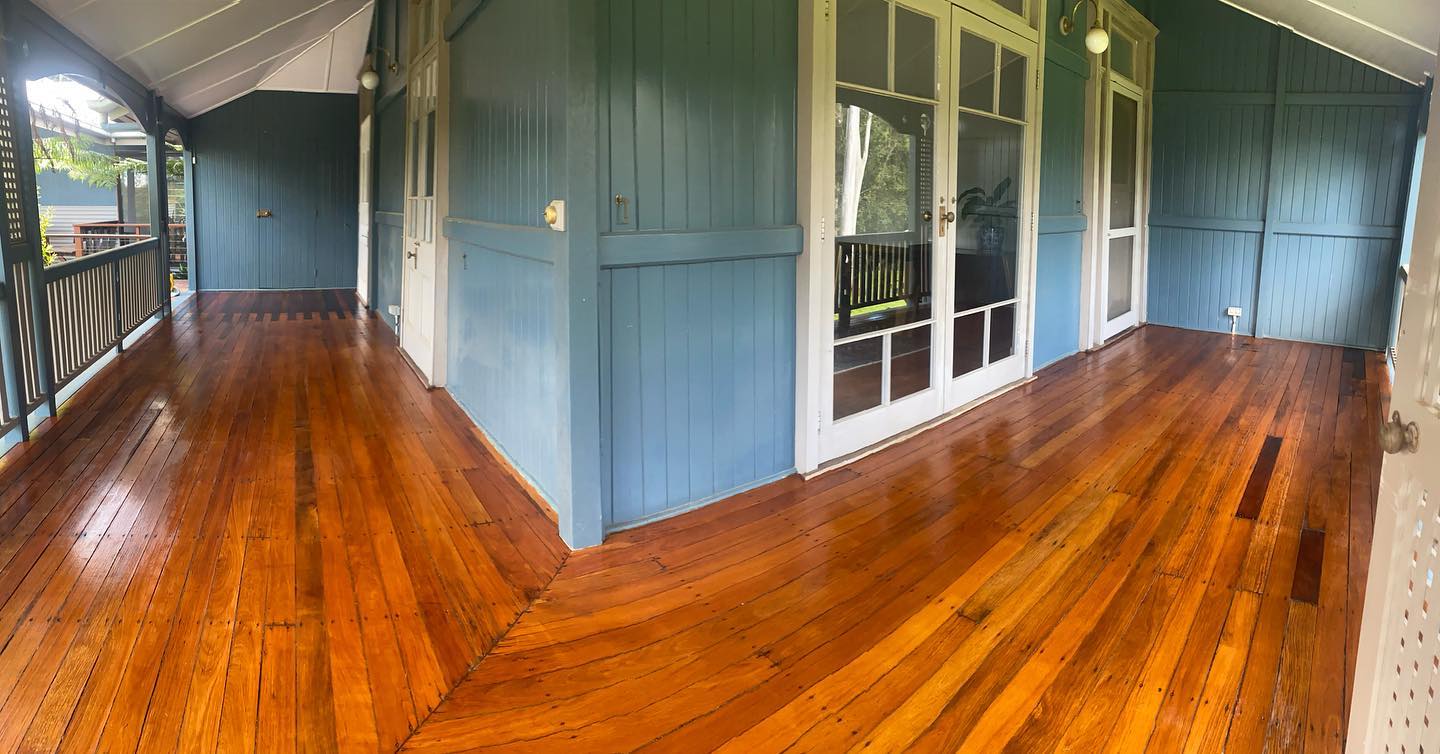 Wide view of an oiled timber verandah wrapping around a blue house