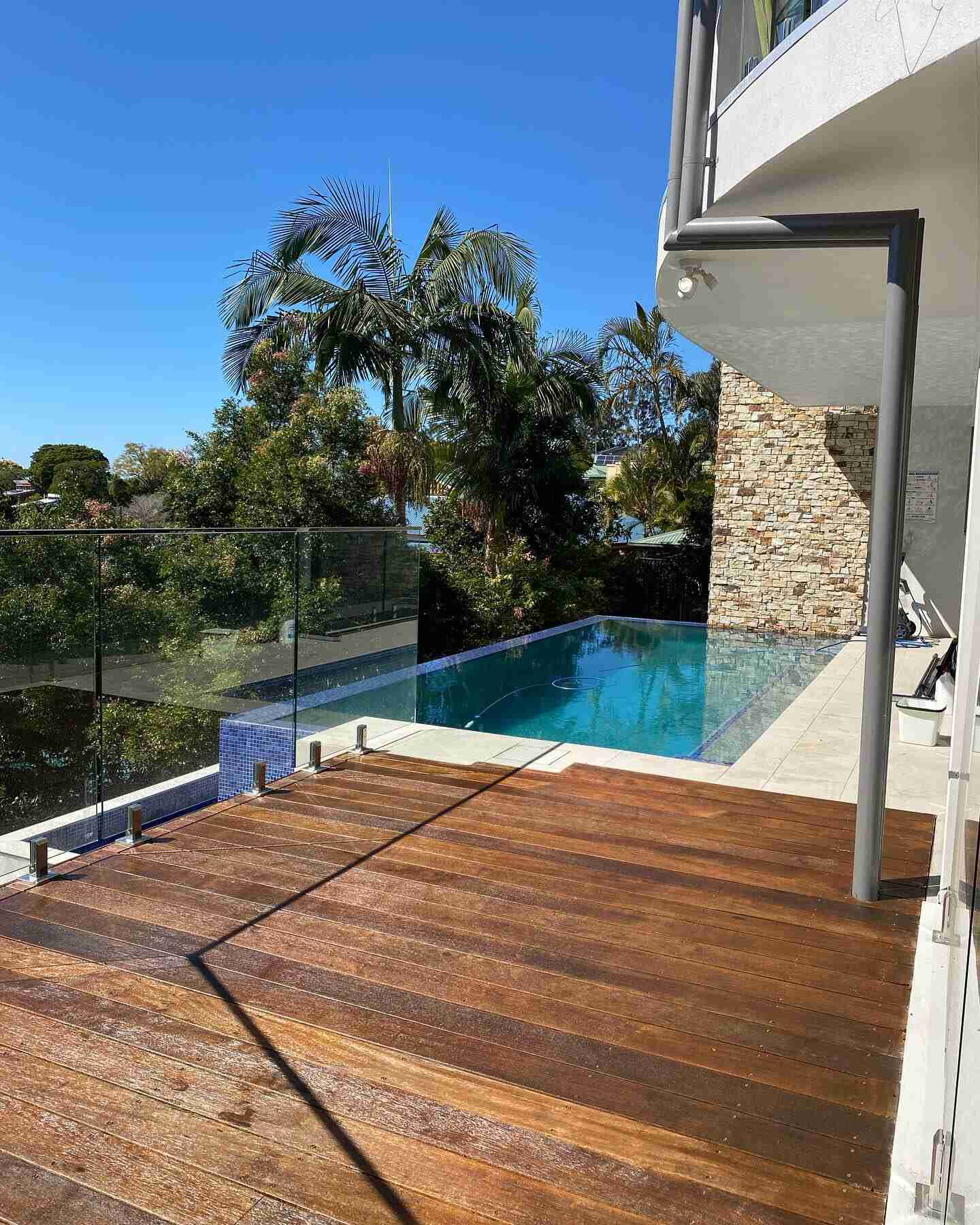 Oiled timber deck above an infinity-edge pool with glass balustrade