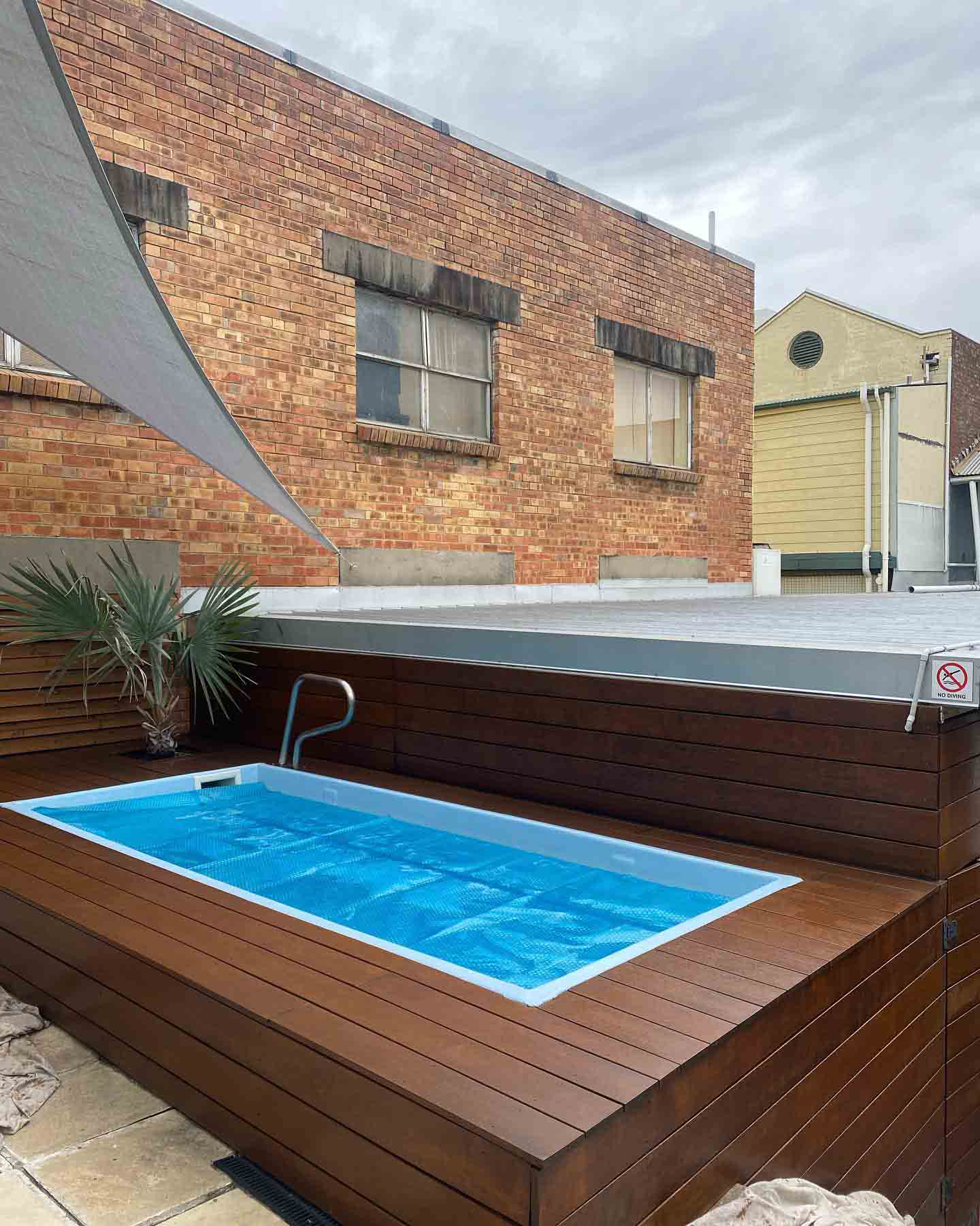 Plunge pool set into a raised timber deck, with a shade sail overhead