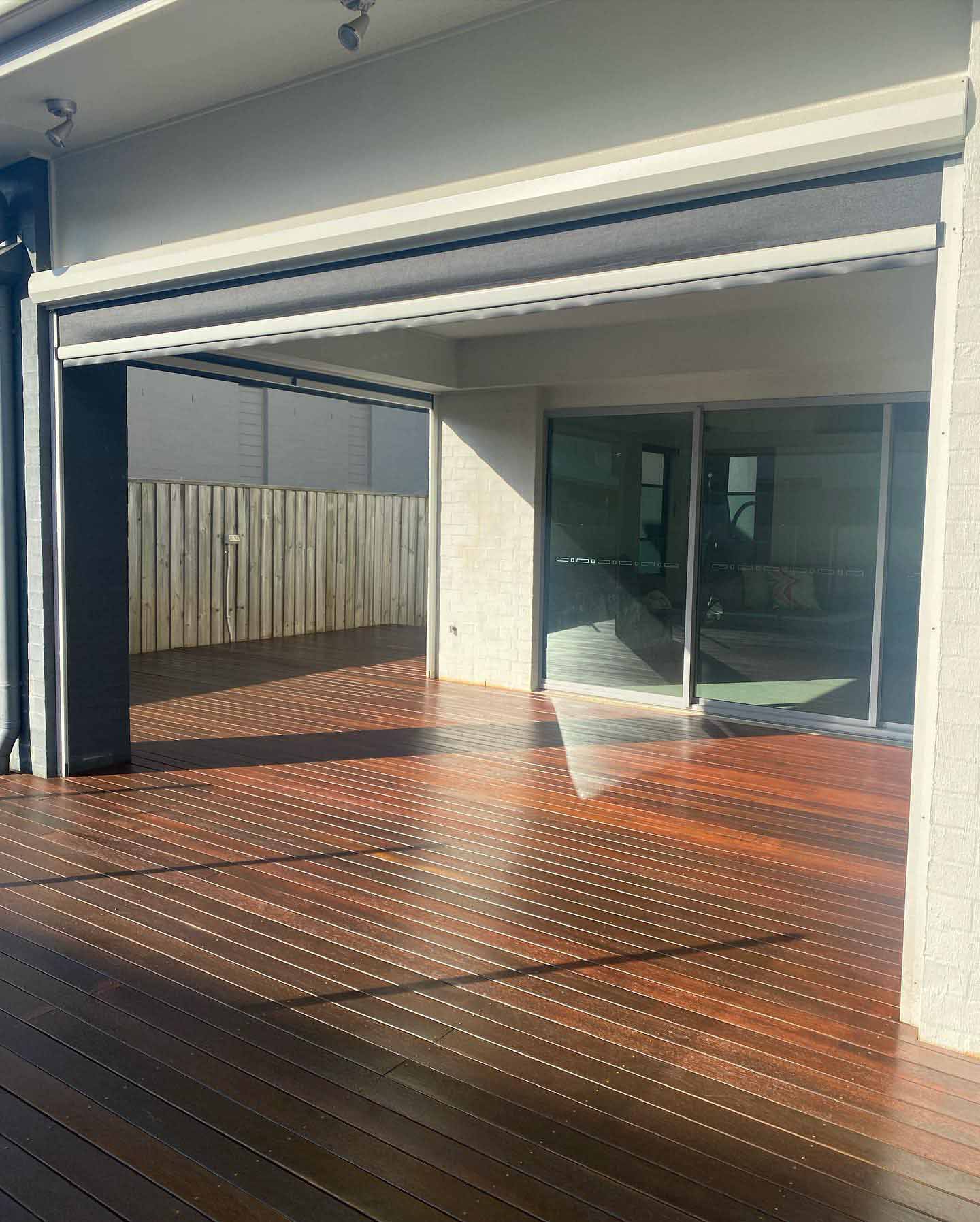Oiled timber deck under a patio with a retractable screen blind