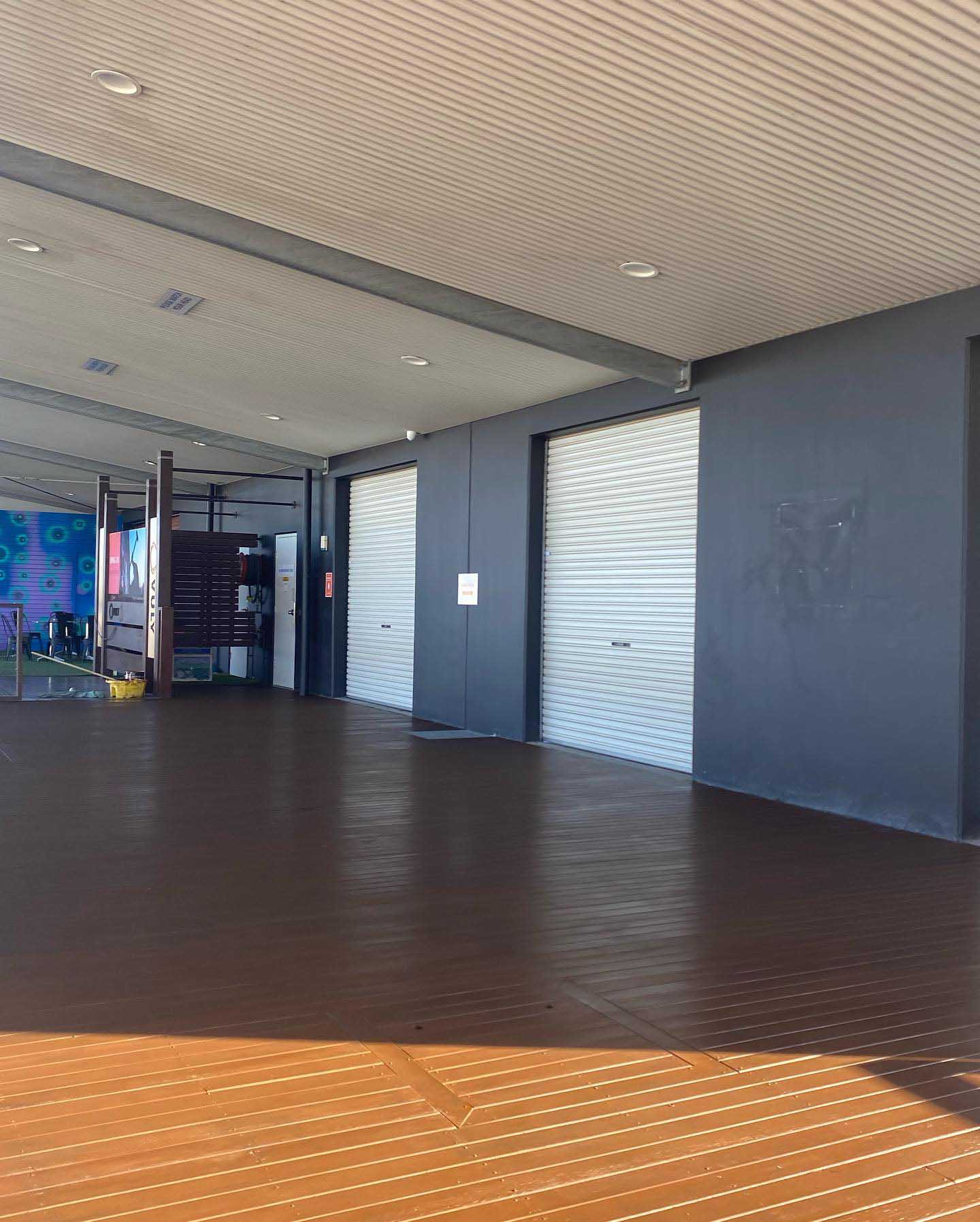 Brown-coated deck under a large covered area beside roller doors