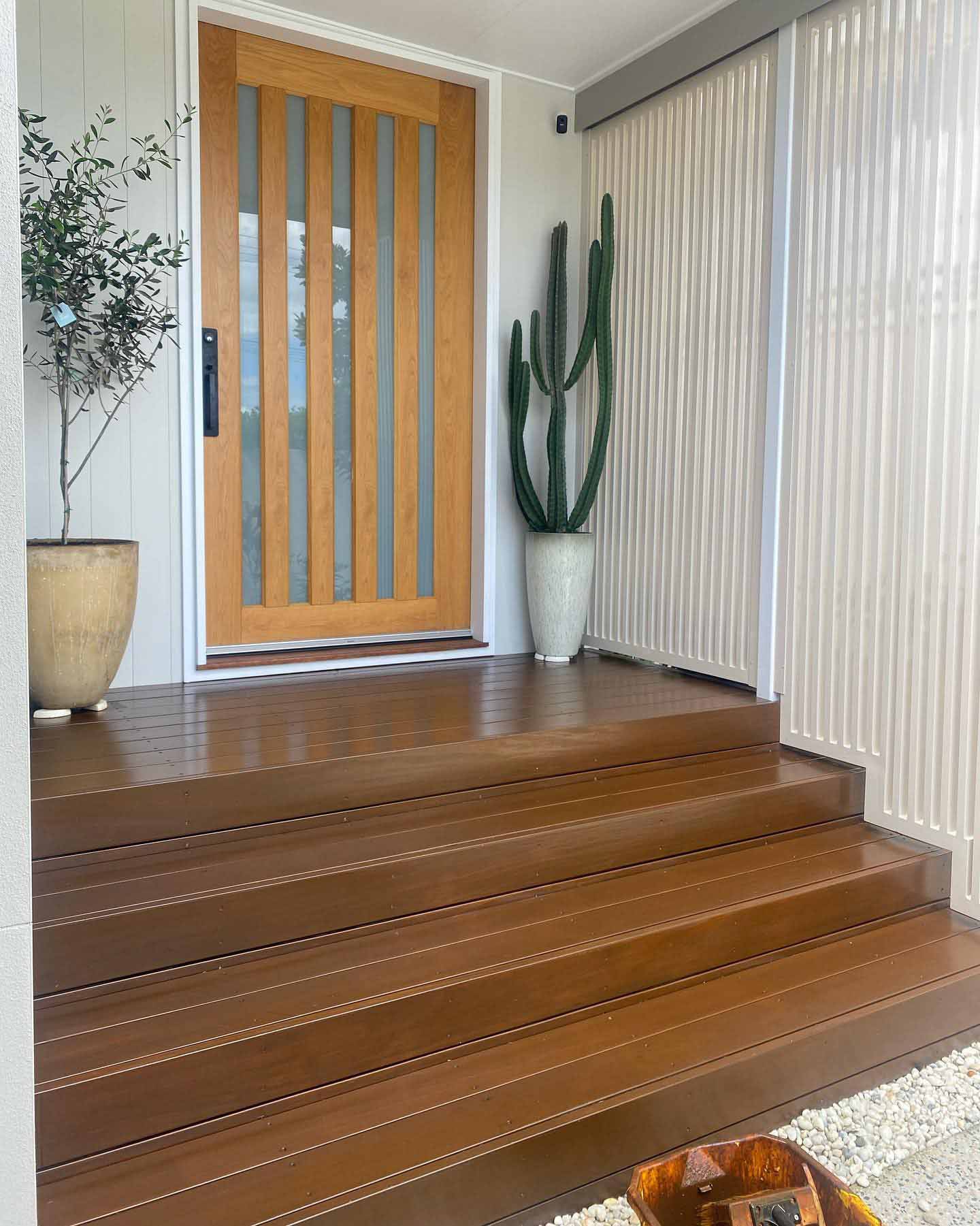 Timber steps and landing at a timber front door with potted plants