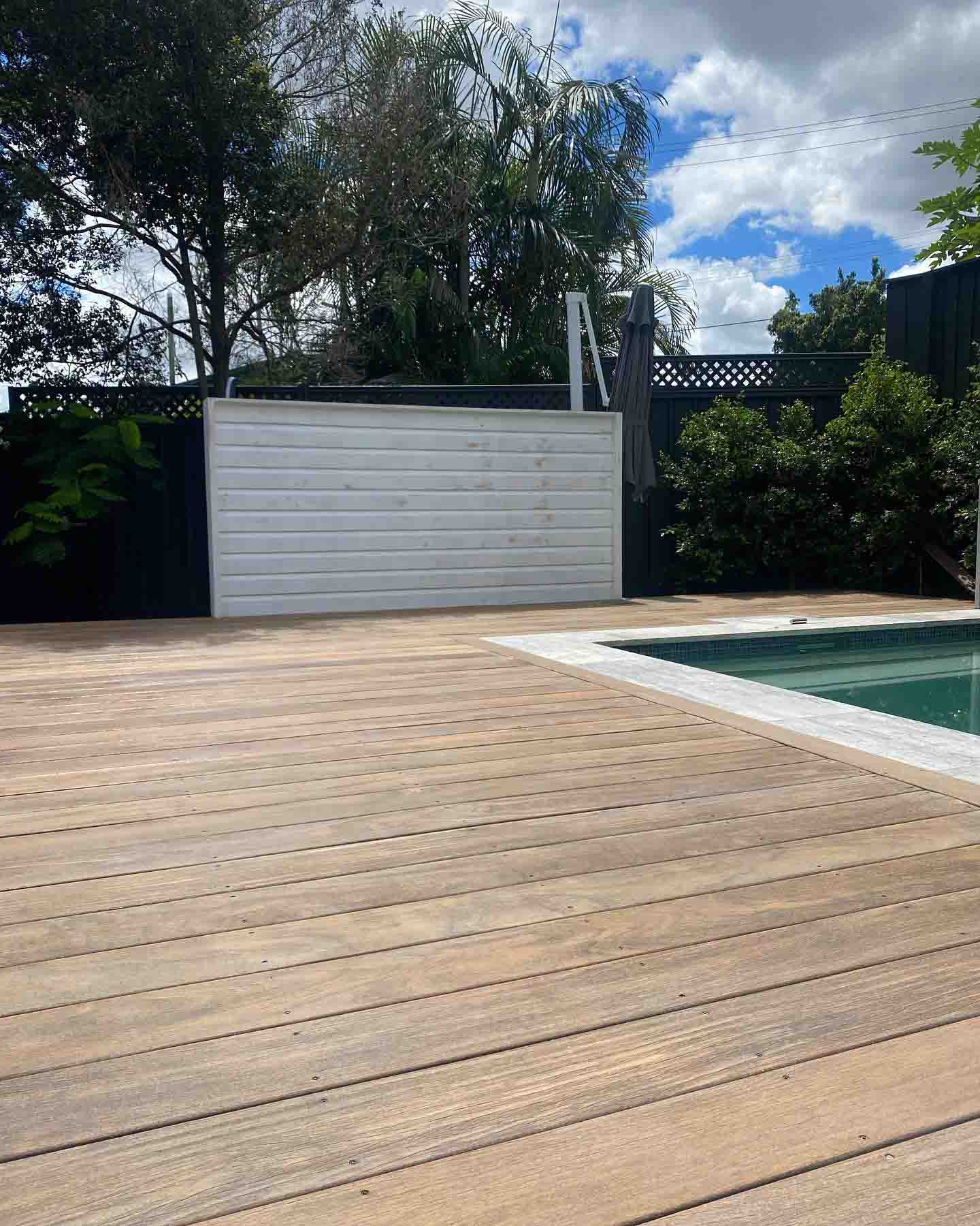 Bare sanded timber deck beside a pool and a white storage box
