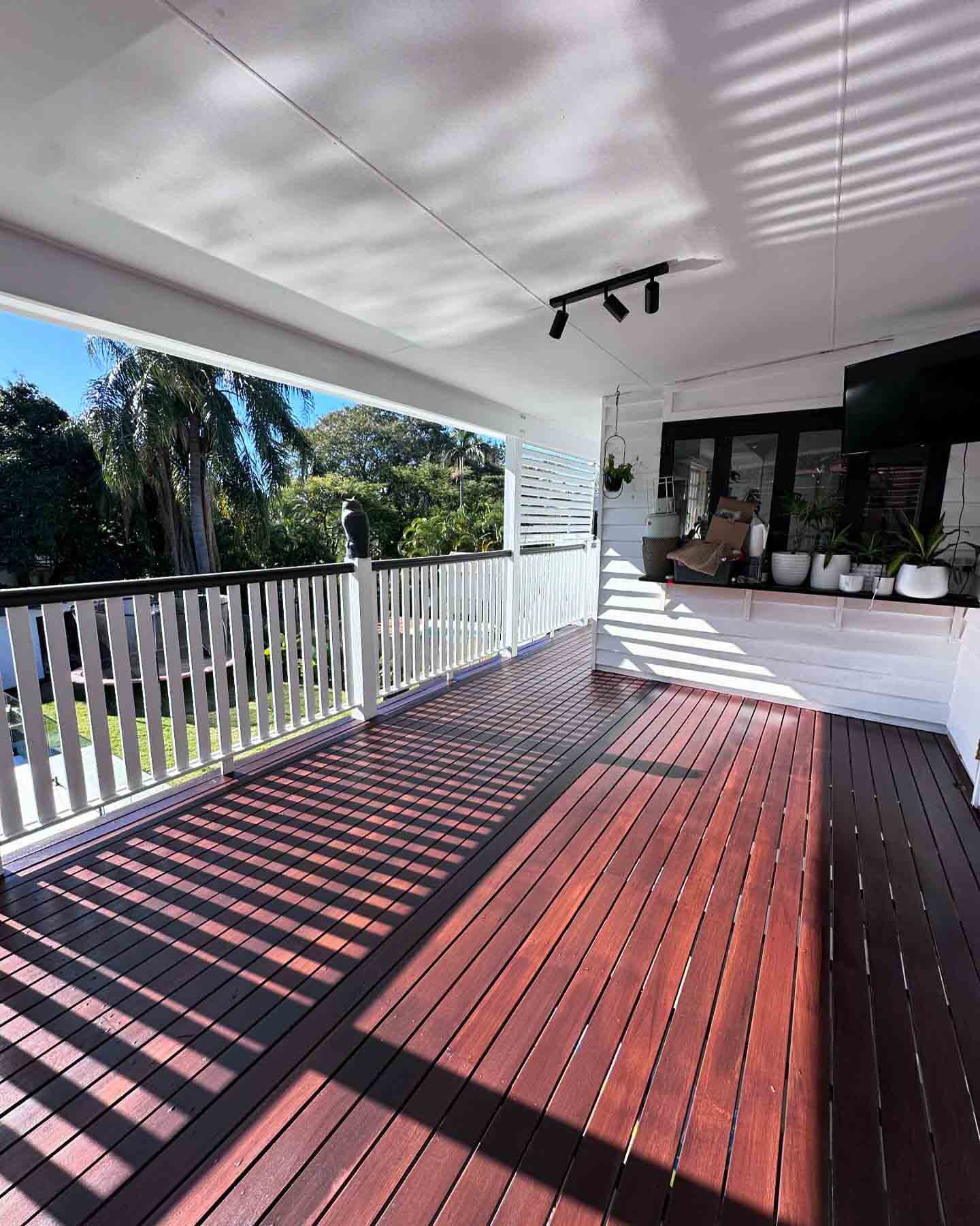 Covered timber deck with white balustrade and an outdoor kitchen bench