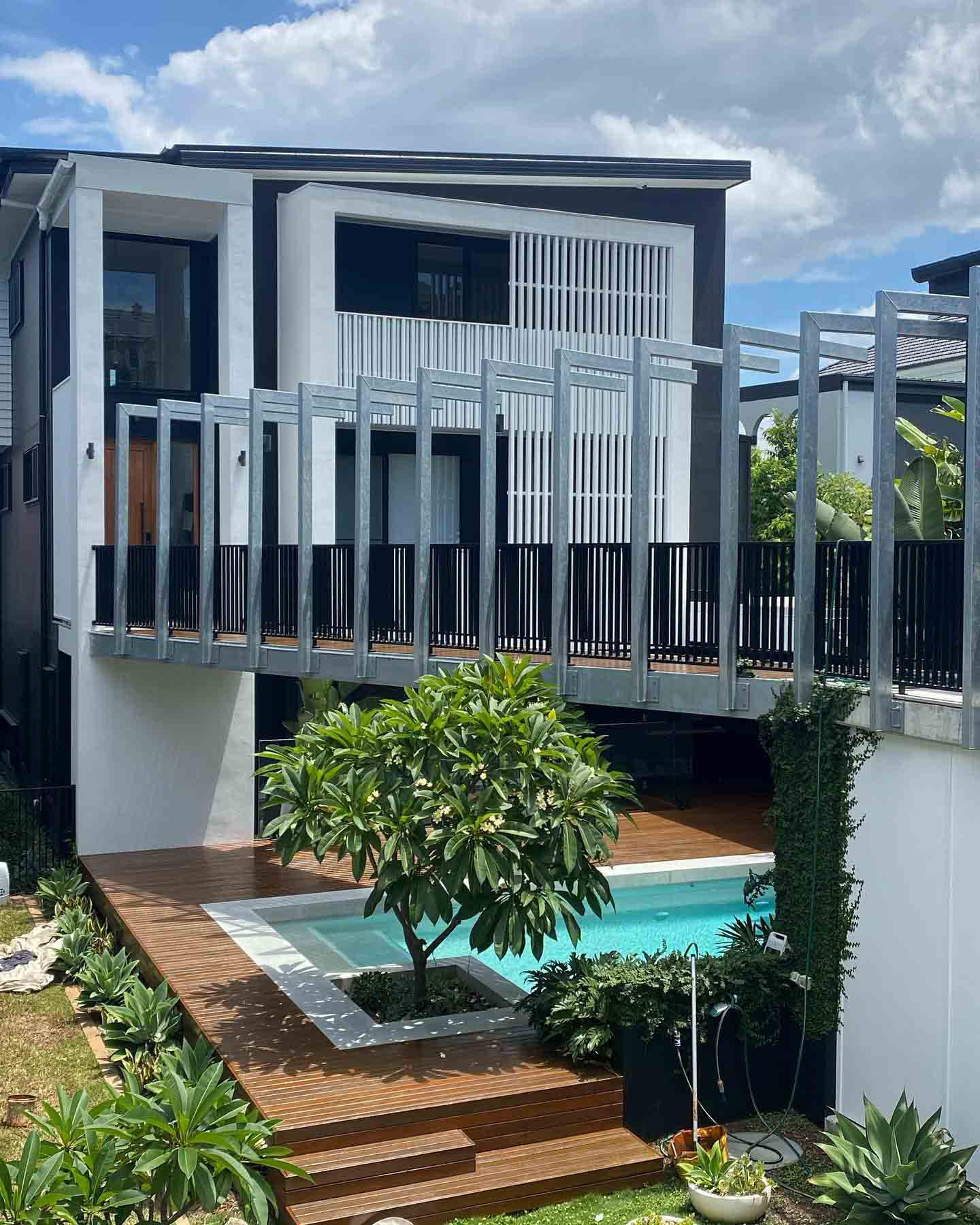 Modern two-storey house with a timber pool deck and steps in the courtyard