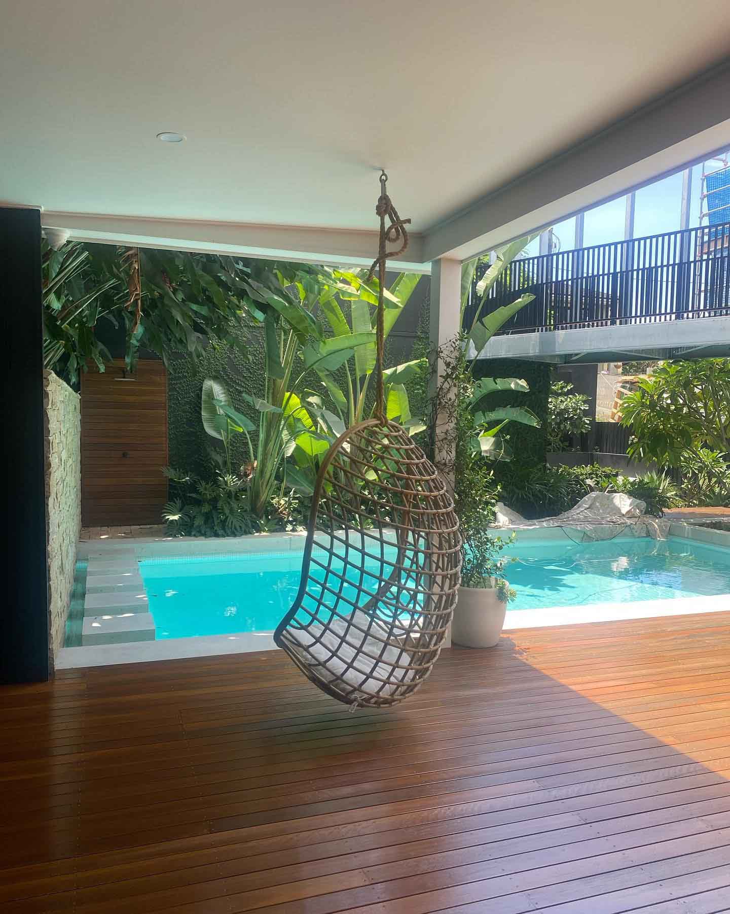 Oiled timber deck with a hanging egg chair beside a pool