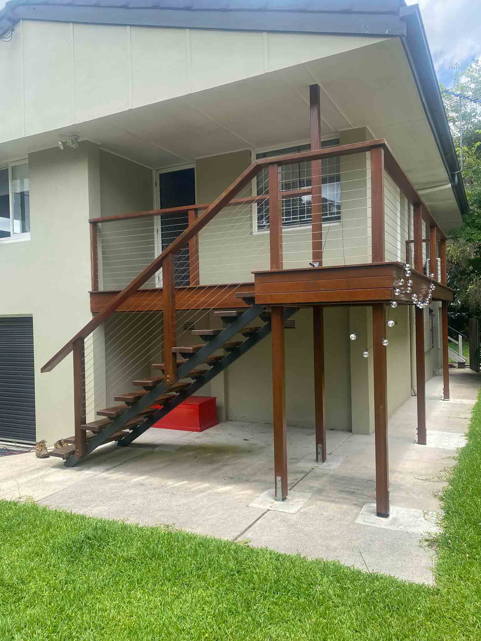 Elevated timber deck with timber stairs and wire balustrade on a two-storey house