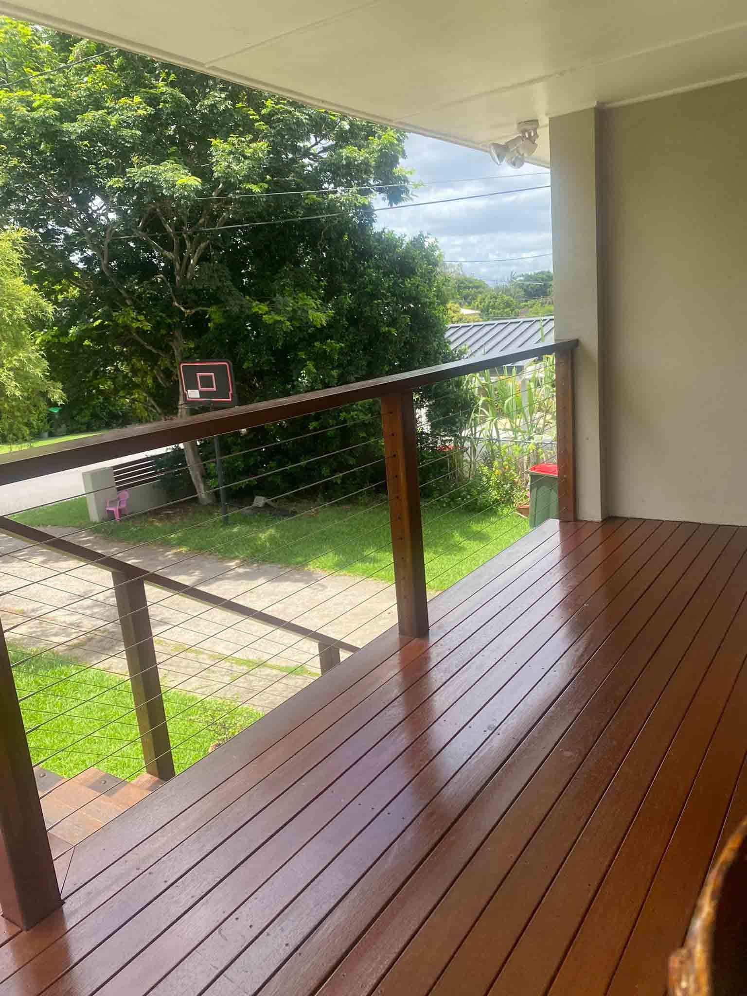 Oiled timber deck with timber and wire balustrade overlooking a yard
