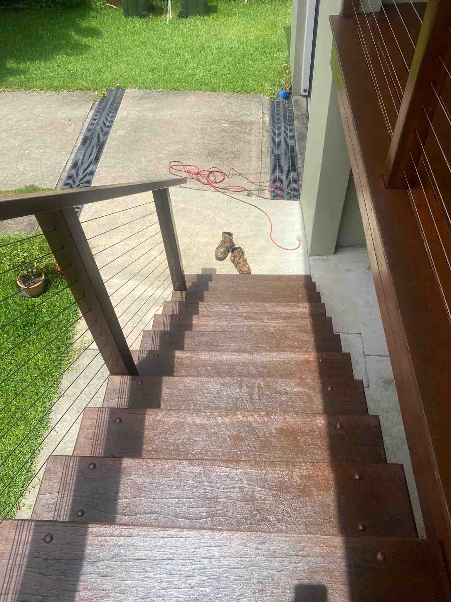 Oiled timber stairs leading down to a driveway, seen from the top