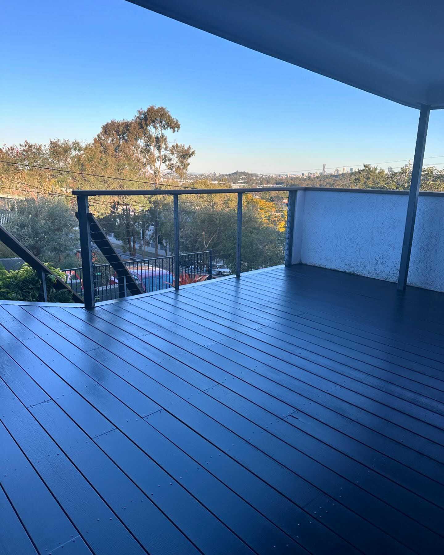 Dark-coated deck with black and glass balustrade overlooking treetops