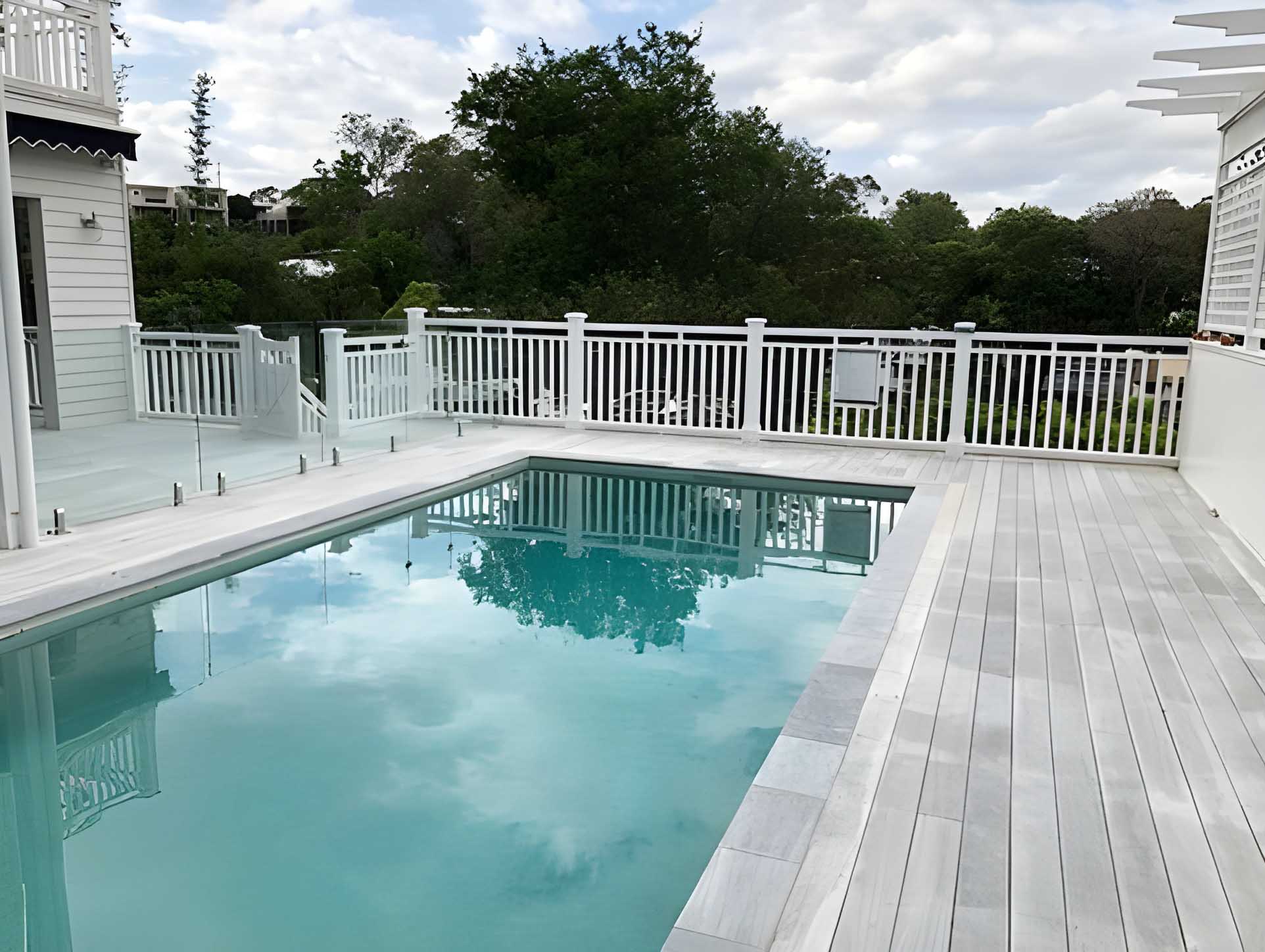 Pale grey deck boards along a pool with white balustrade