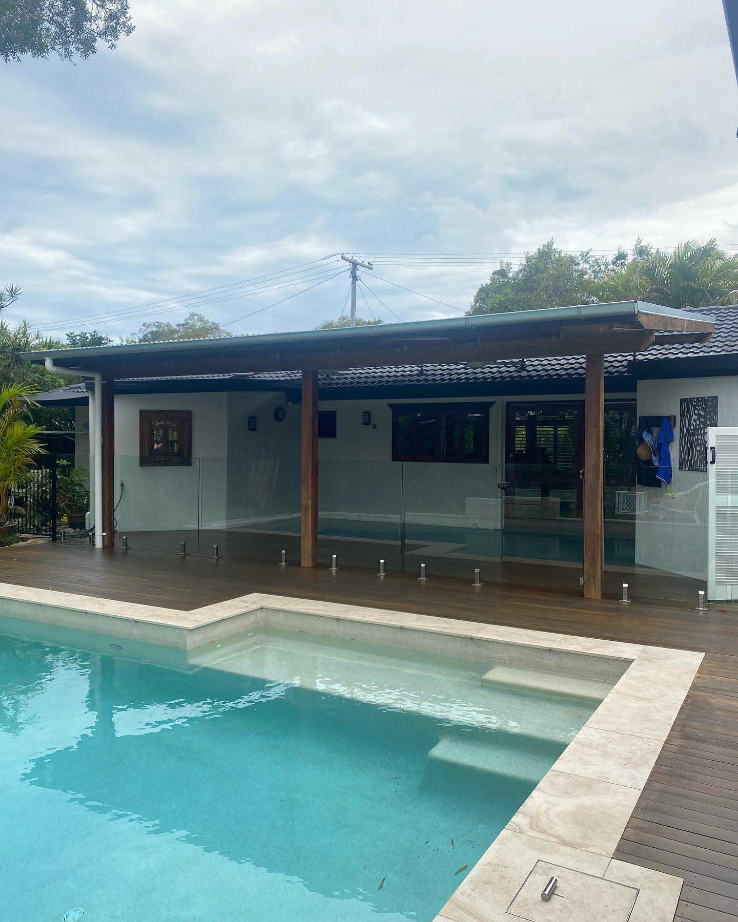 Timber deck around a pool with a timber-posted pavilion behind