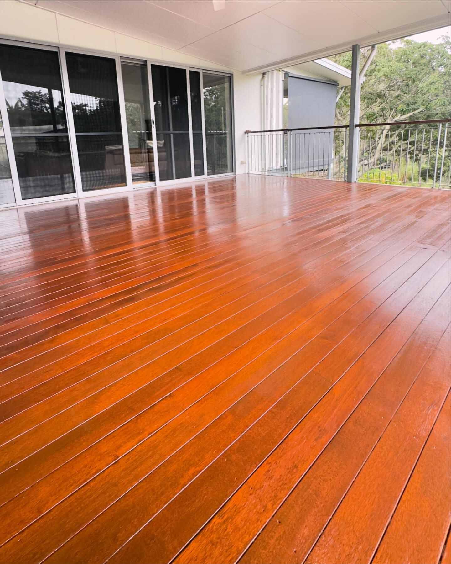 Glossy orange-toned oiled deck outside glass sliding doors