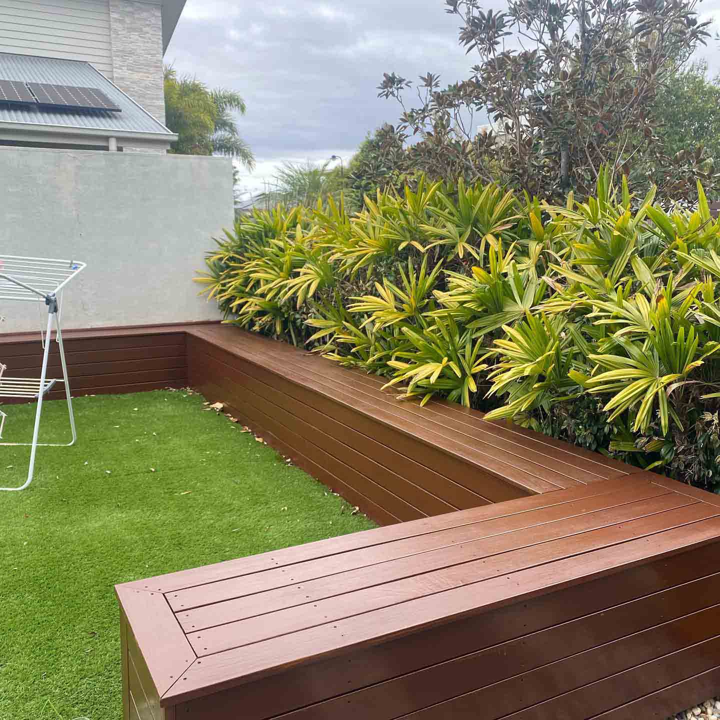 Timber bench seat bordering artificial turf and a garden bed