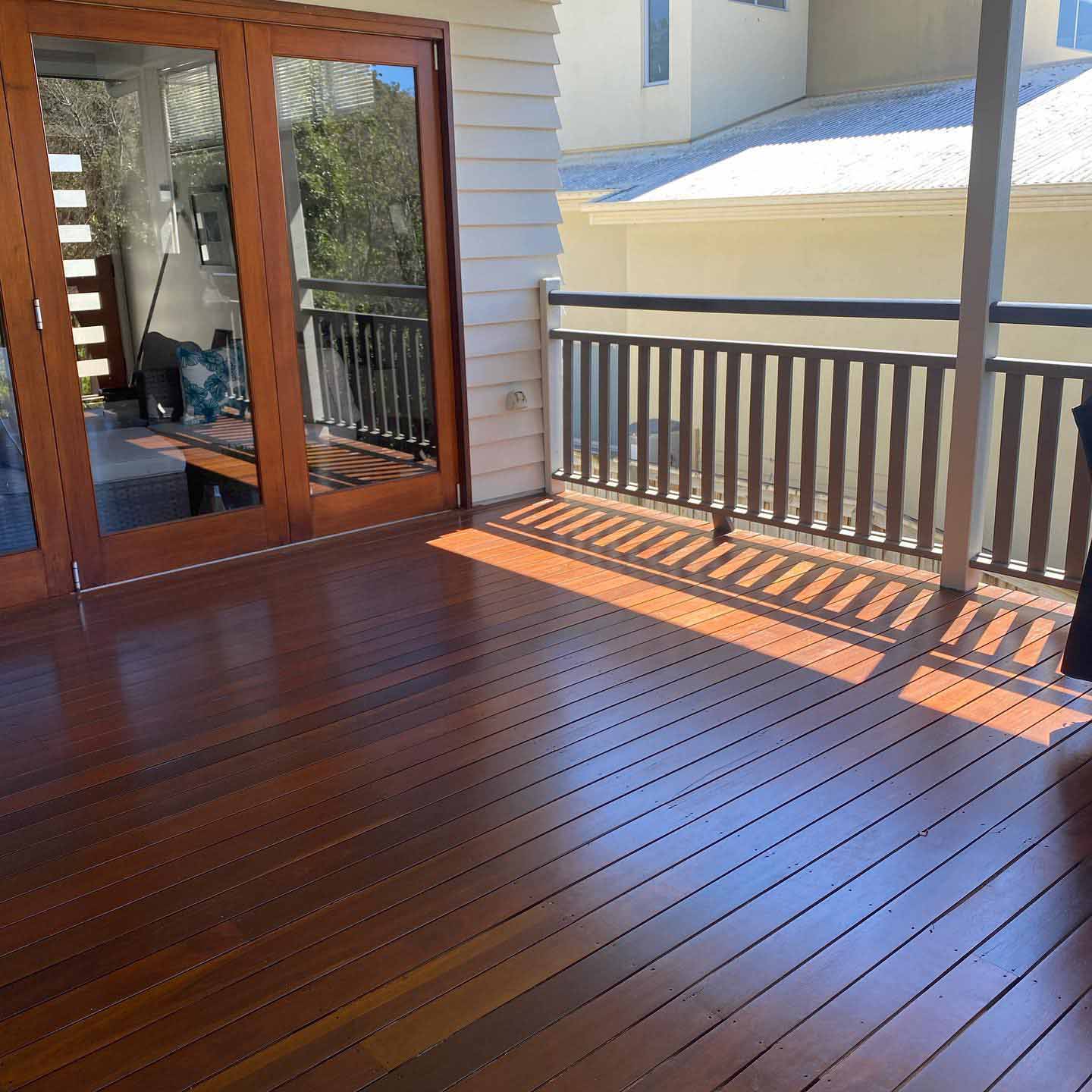Oiled timber deck with dark timber balustrade outside timber French doors