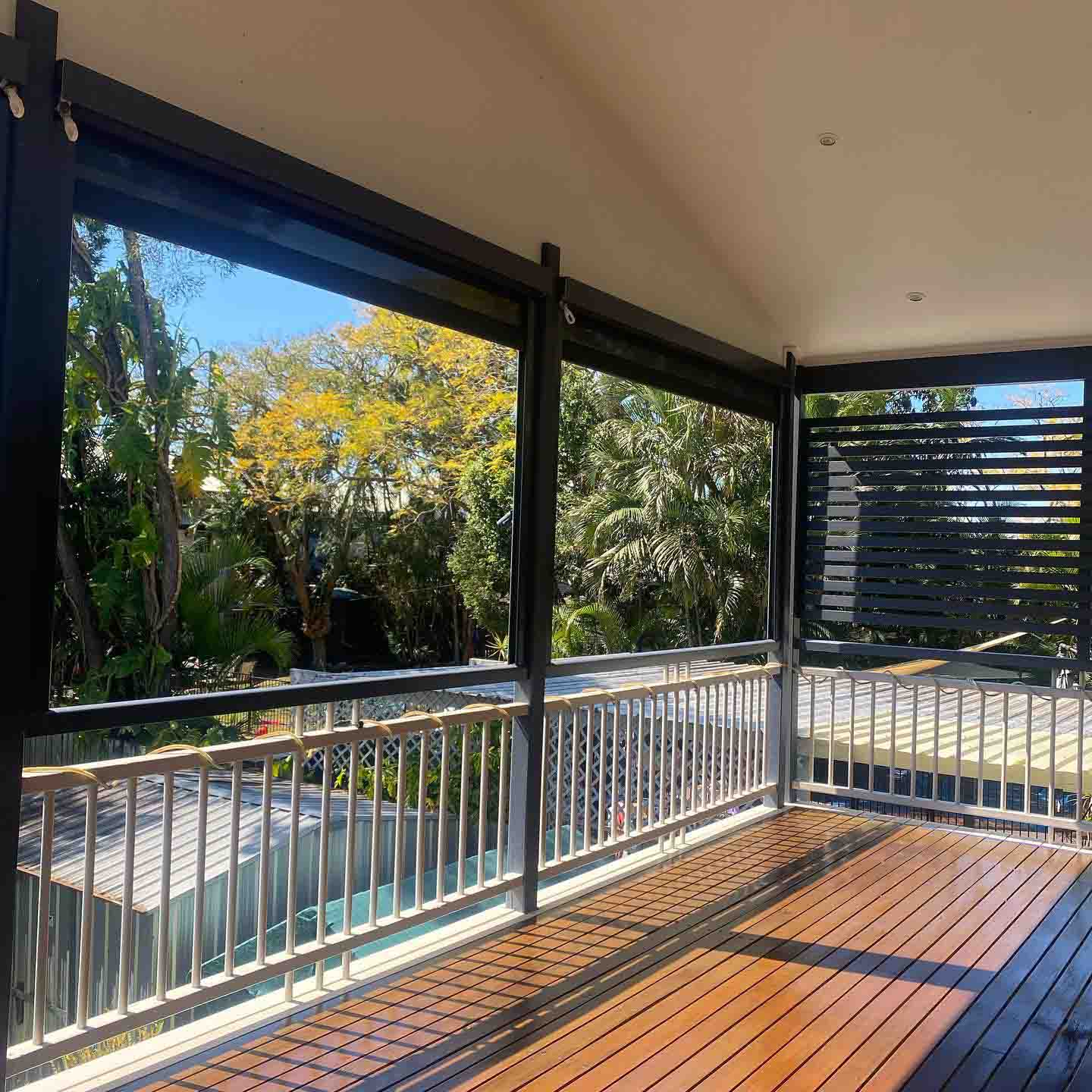 Oiled timber deck under a raked roof with aluminium balustrade and slatted screen
