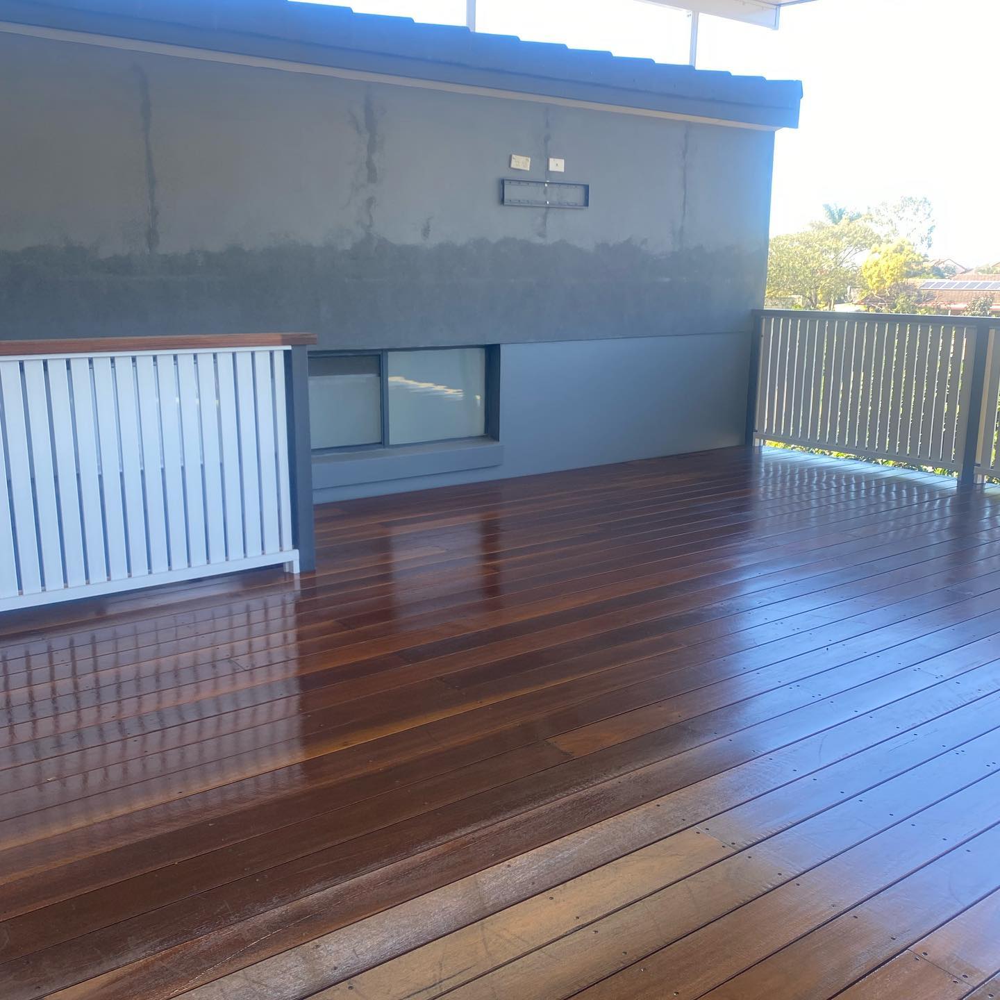 Glossy oiled timber deck with a white slatted screen and timber balustrade
