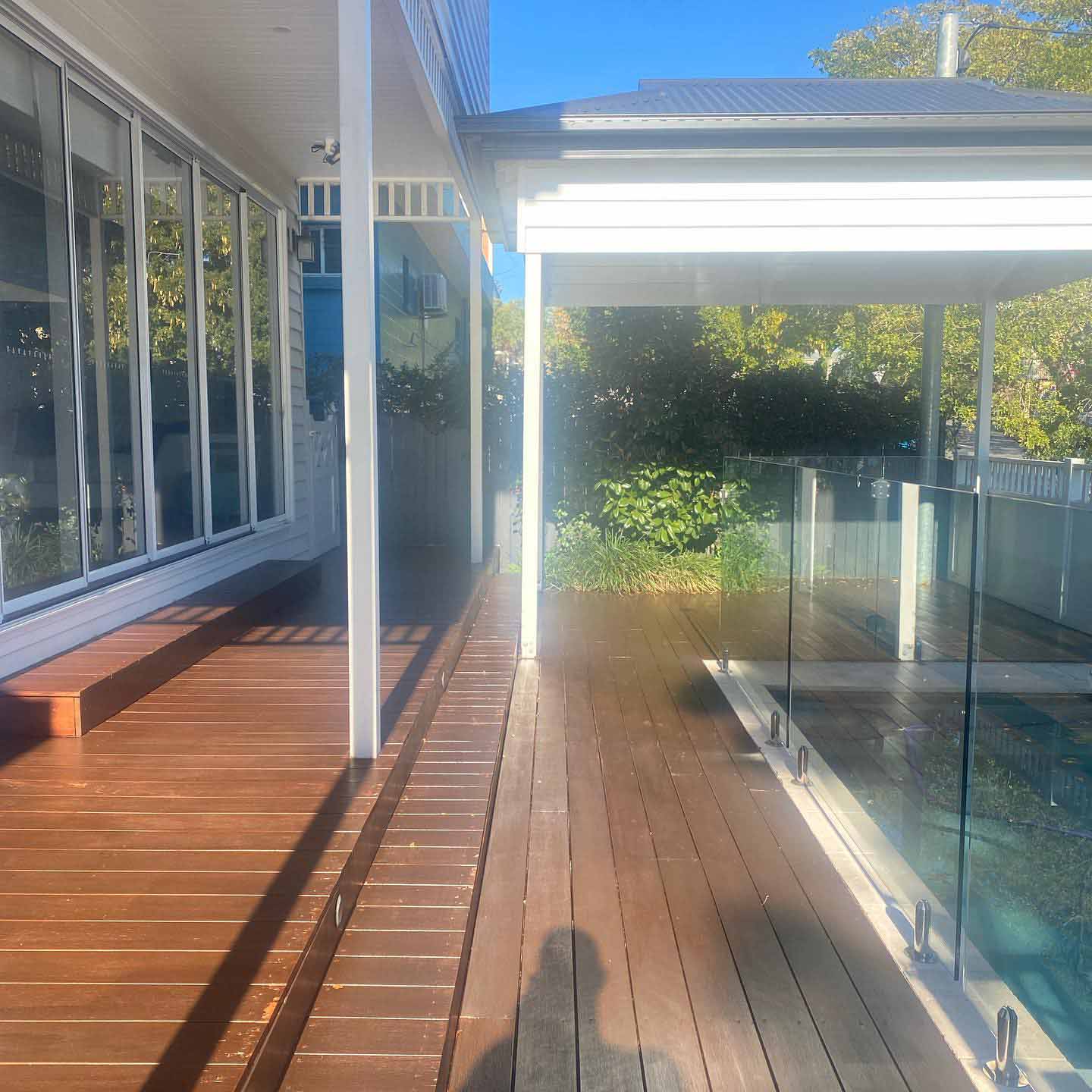 Oiled timber deck between a glass-walled room and a glass pool fence