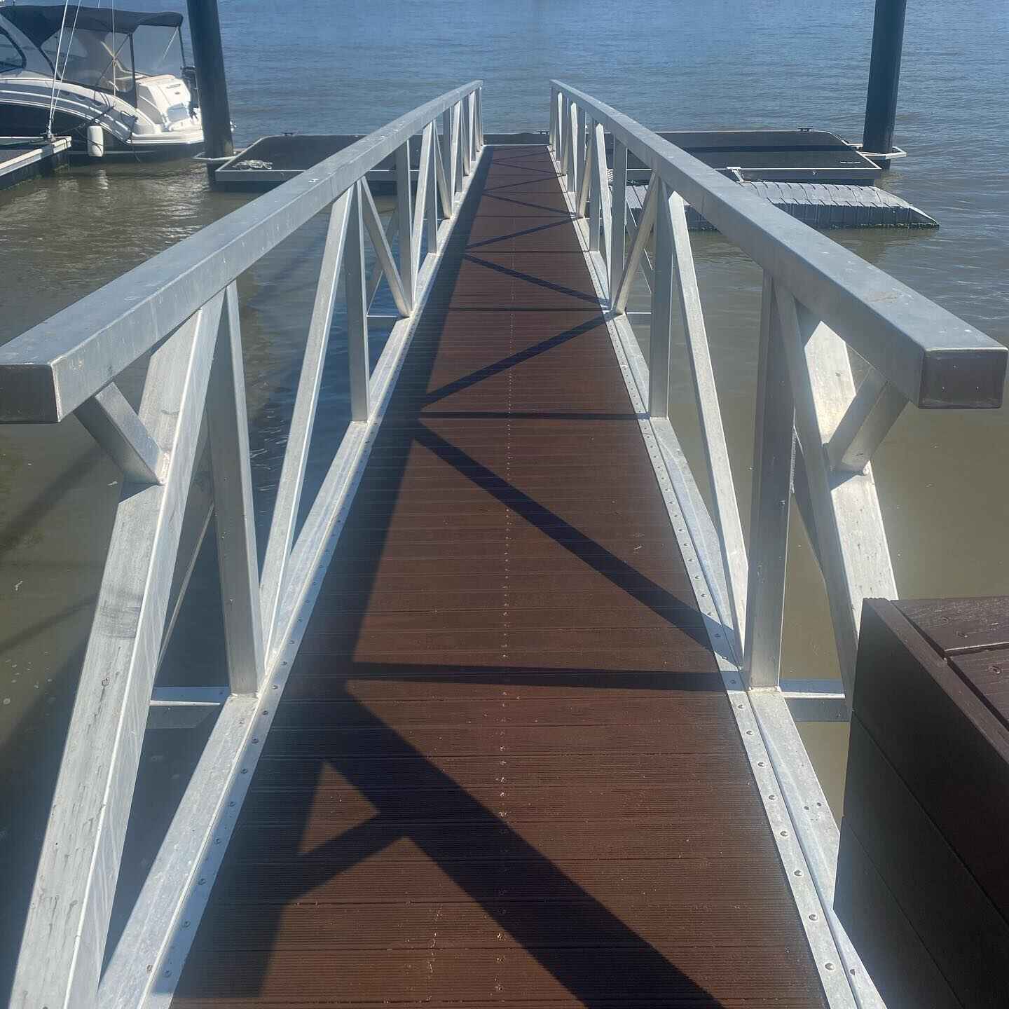 Timber jetty walkway with aluminium truss balustrade leading to boats