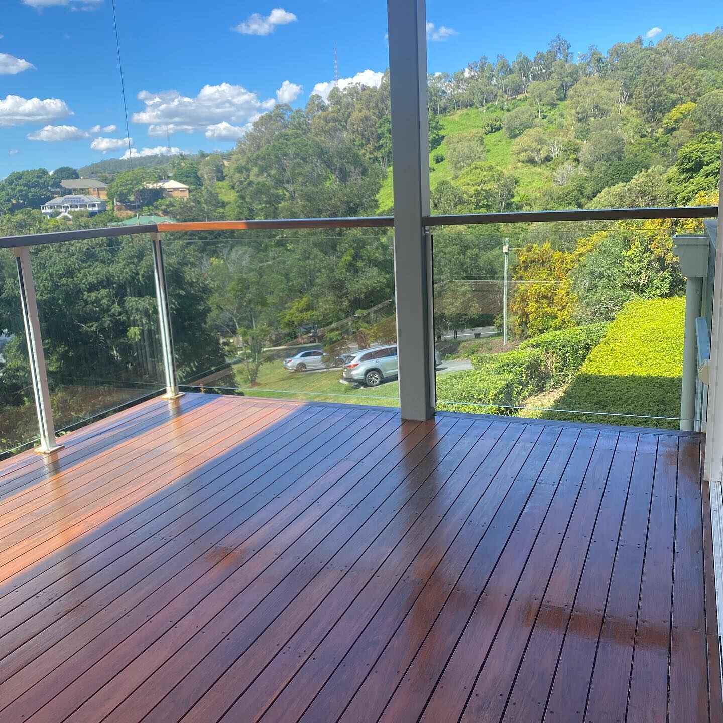 Oiled timber deck with glass balustrade overlooking green hills