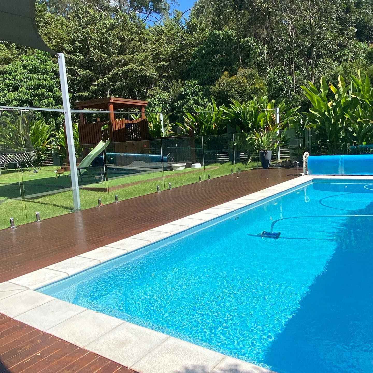 Oiled timber deck along a rectangular pool with glass fencing