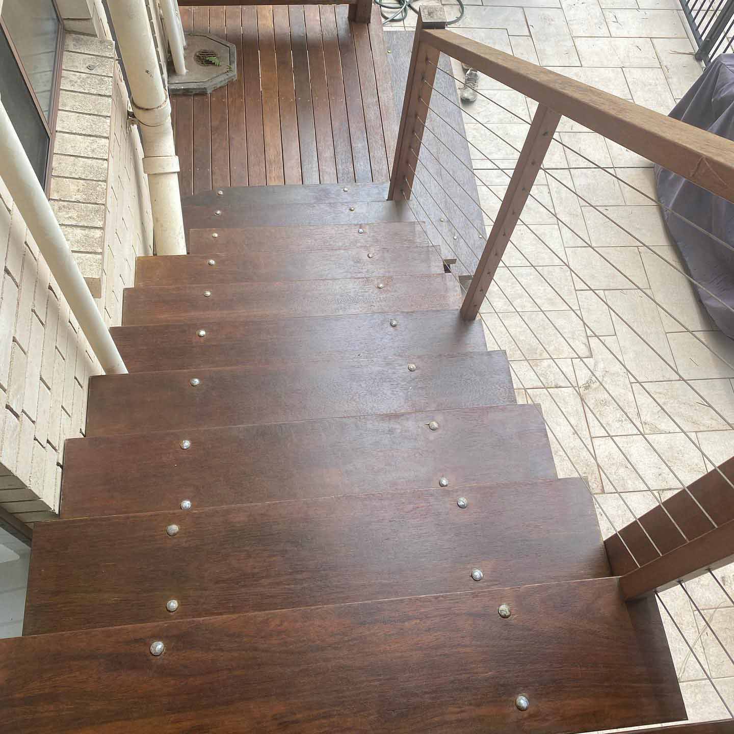 Oiled timber stairs with timber and wire handrail leading down to tiles