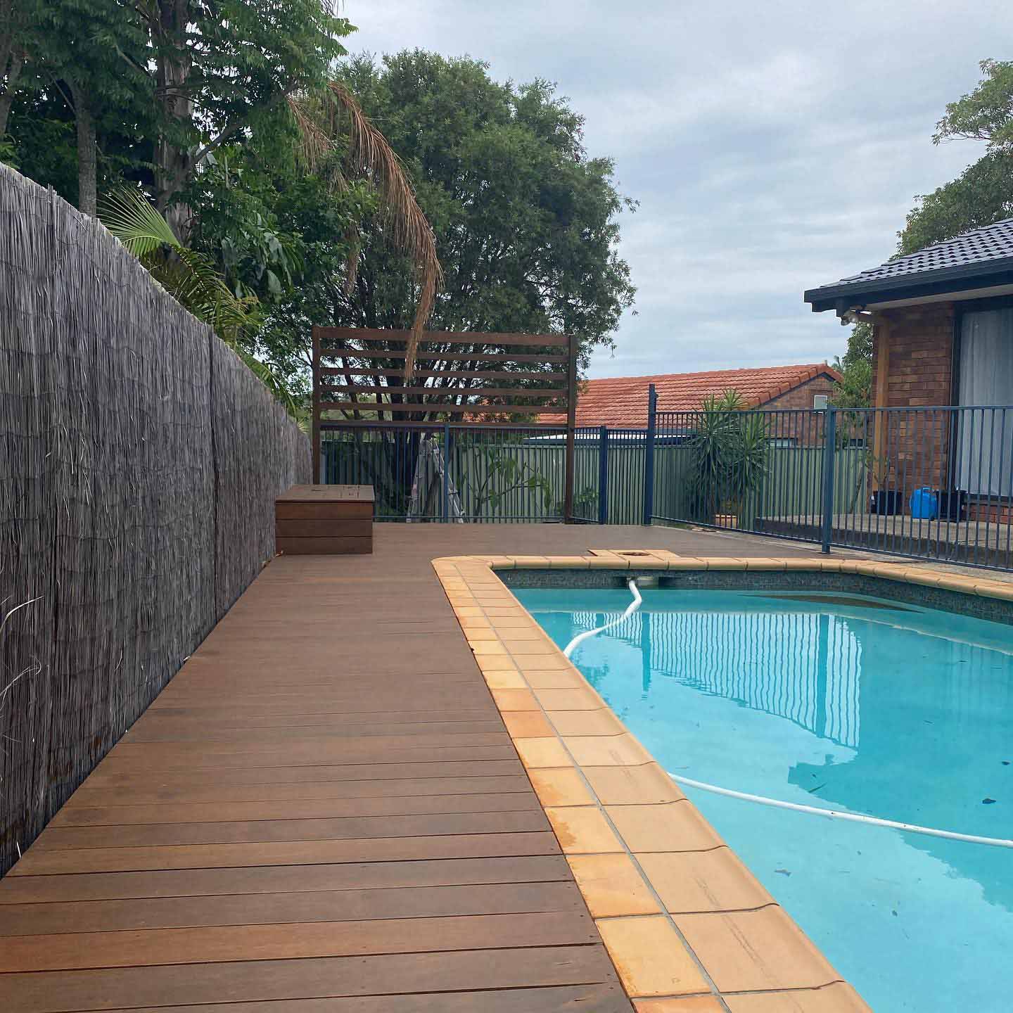 Timber deck beside a pool and a brush fence