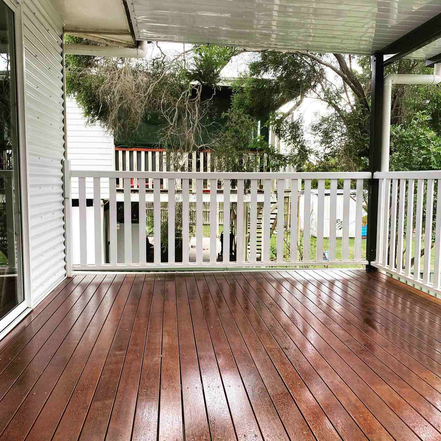 Glossy oiled timber verandah with white timber balustrade overlooking a garden