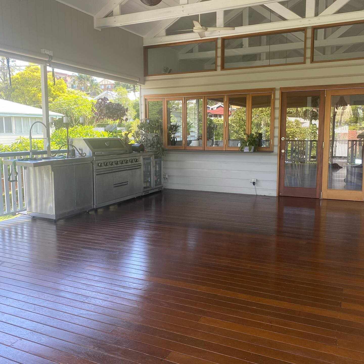 Glossy oiled timber deck under a patio with an outdoor kitchen and timber doors