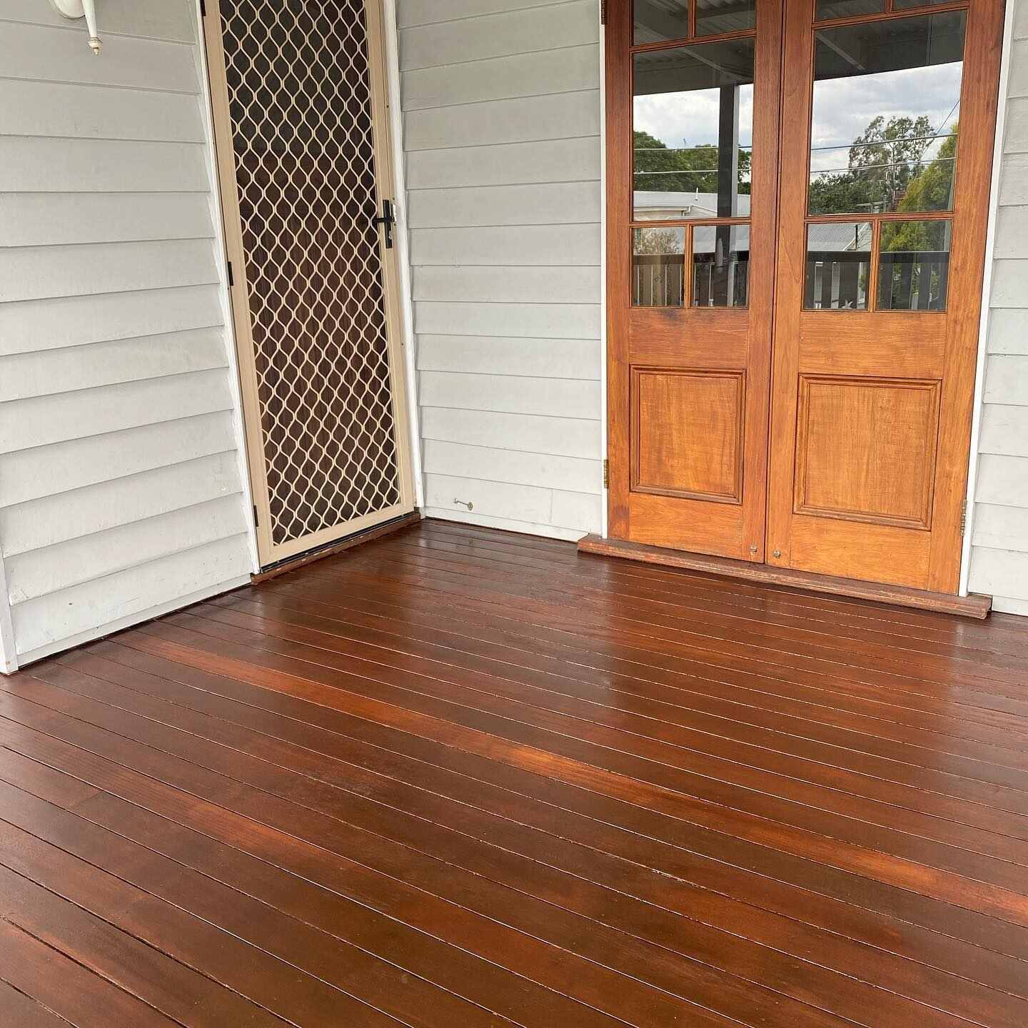Oiled timber verandah outside timber French doors and a security door