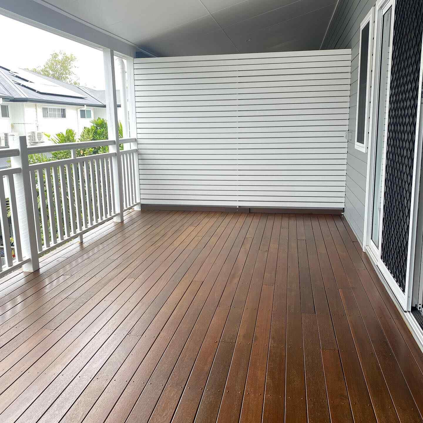 Oiled timber verandah with white balustrade and a white slatted screen