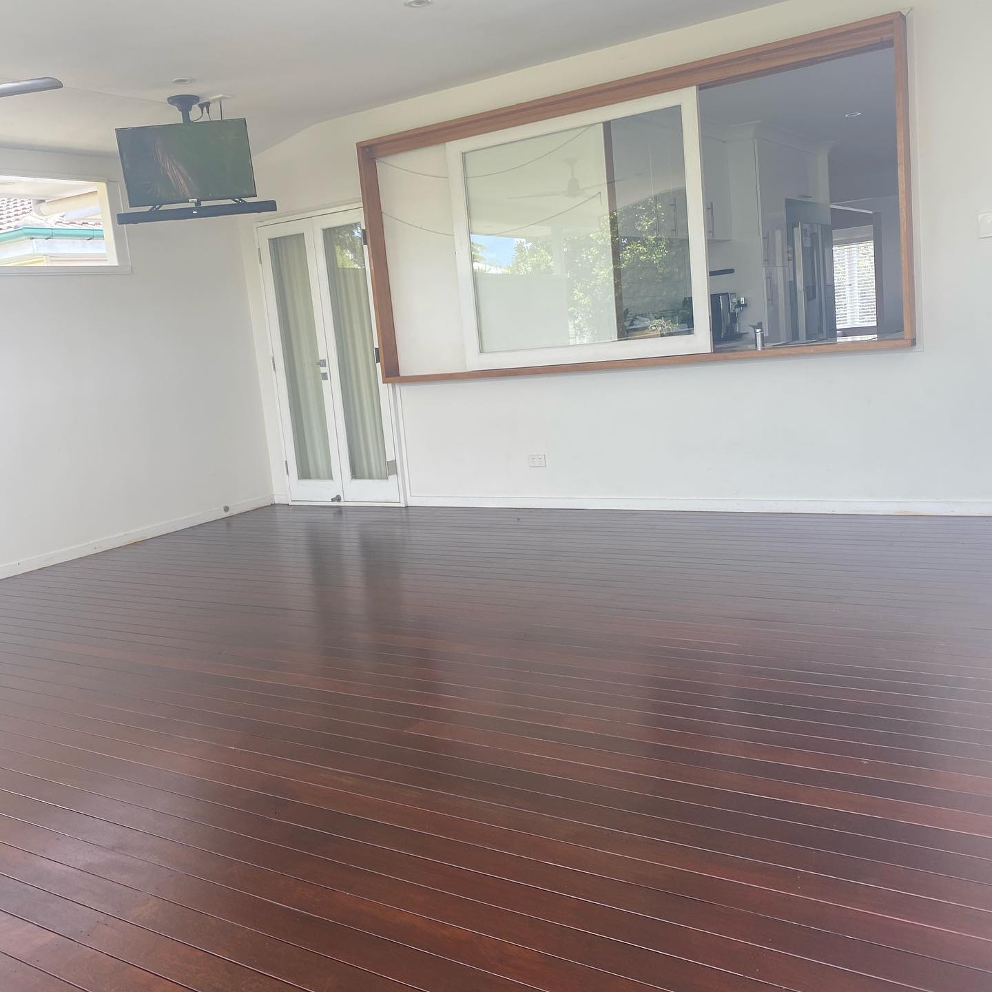 Glossy oiled timber deck in a covered room with a servery window