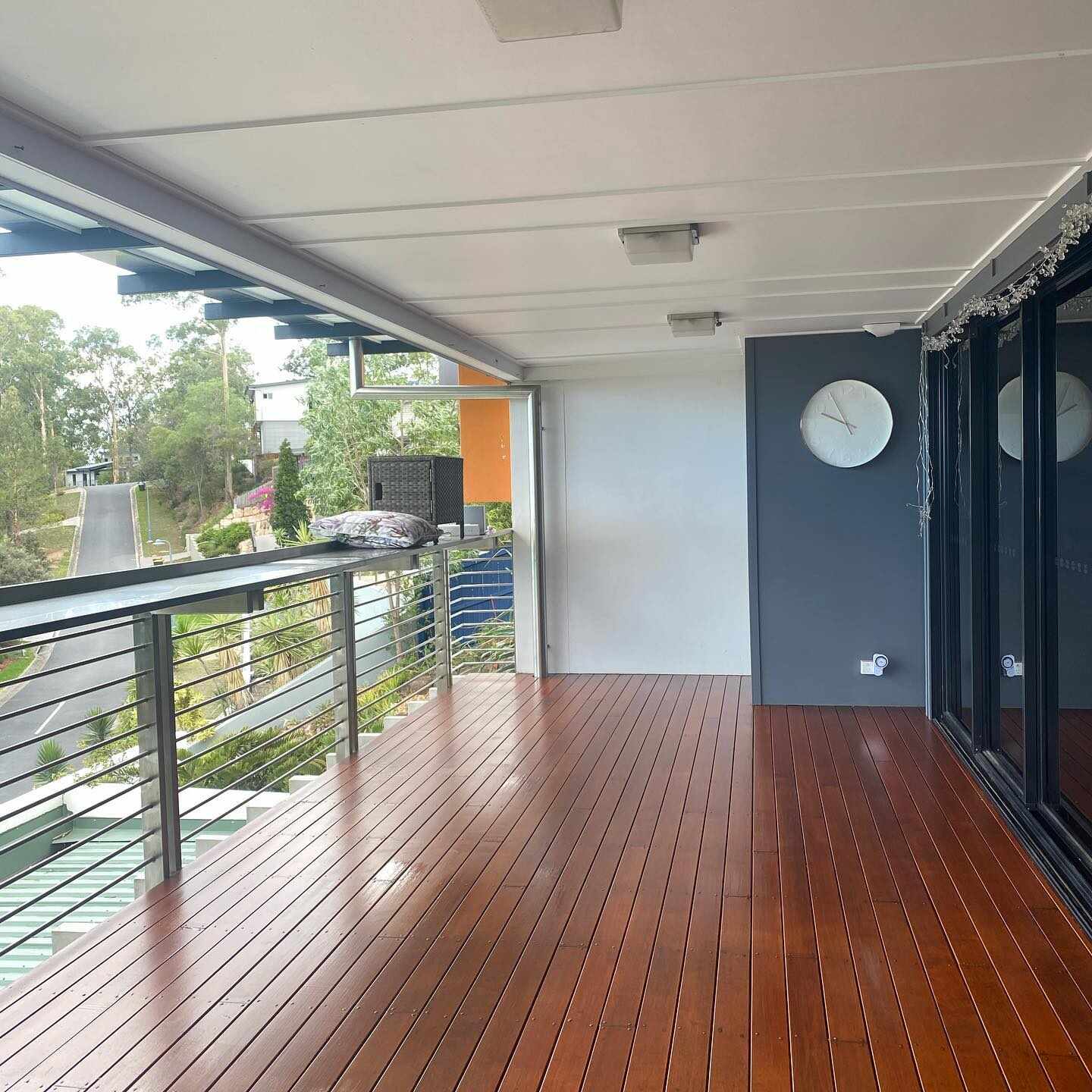 Oiled timber balcony with steel balustrade beside dark sliding doors