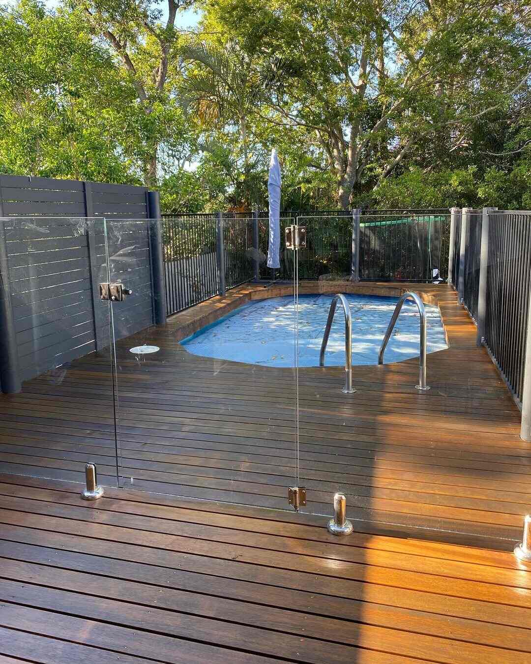 Oiled timber deck around a small pool with glass fencing and steps