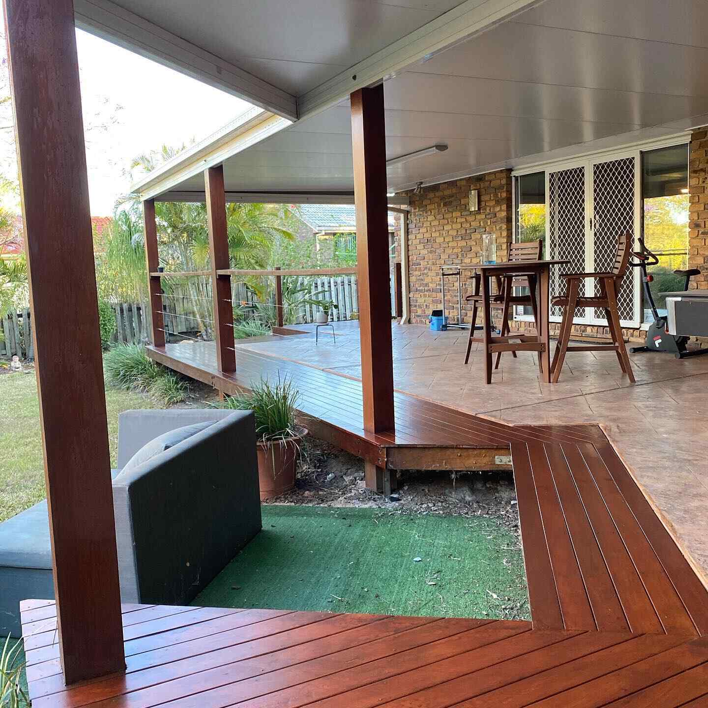 Oiled timber deck wrapping around a timber post and a patch of turf