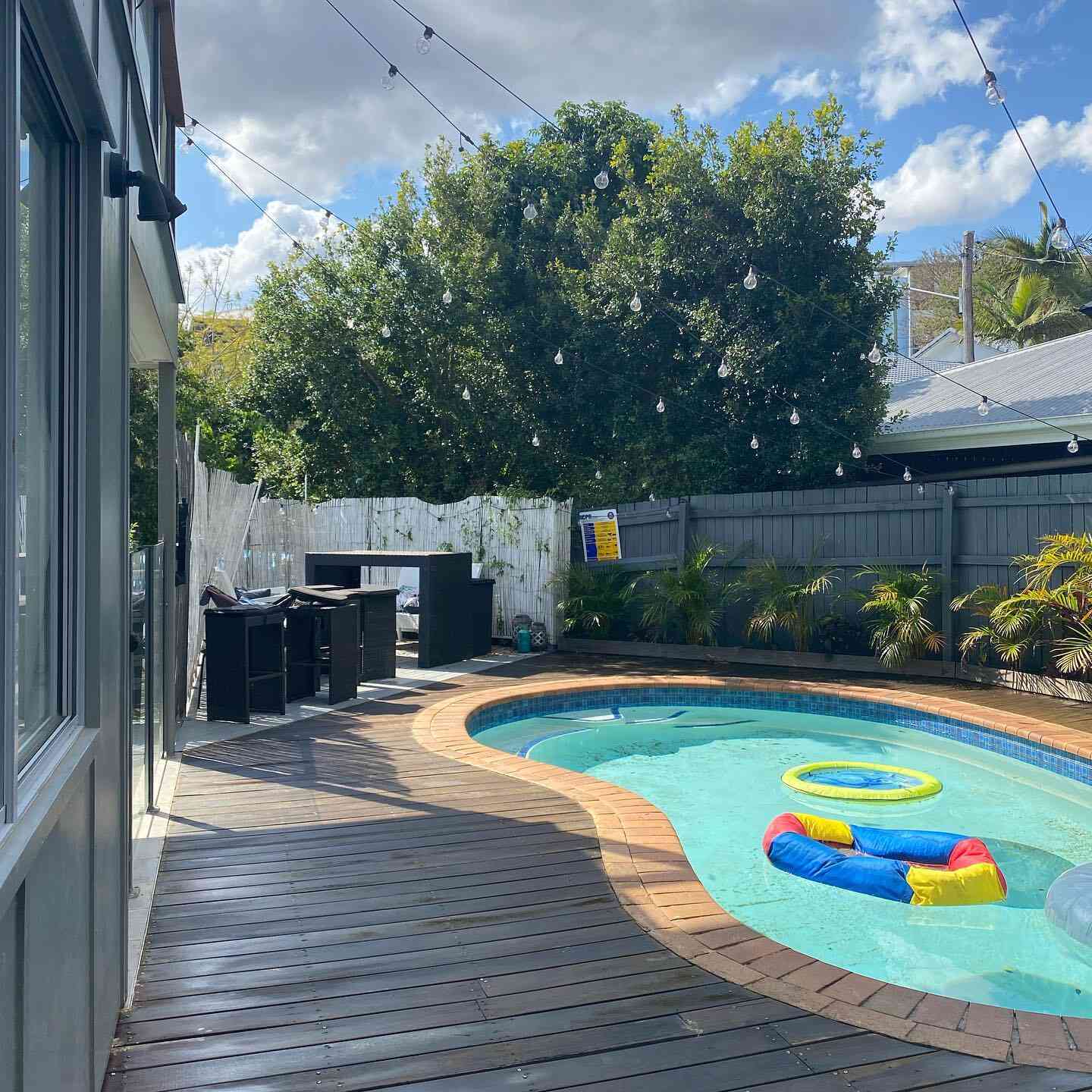 Oiled timber deck around a kidney-shaped pool with pool toys