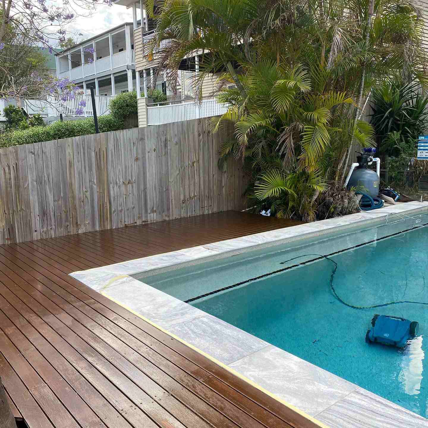 Oiled timber deck around a pool beside a timber paling fence