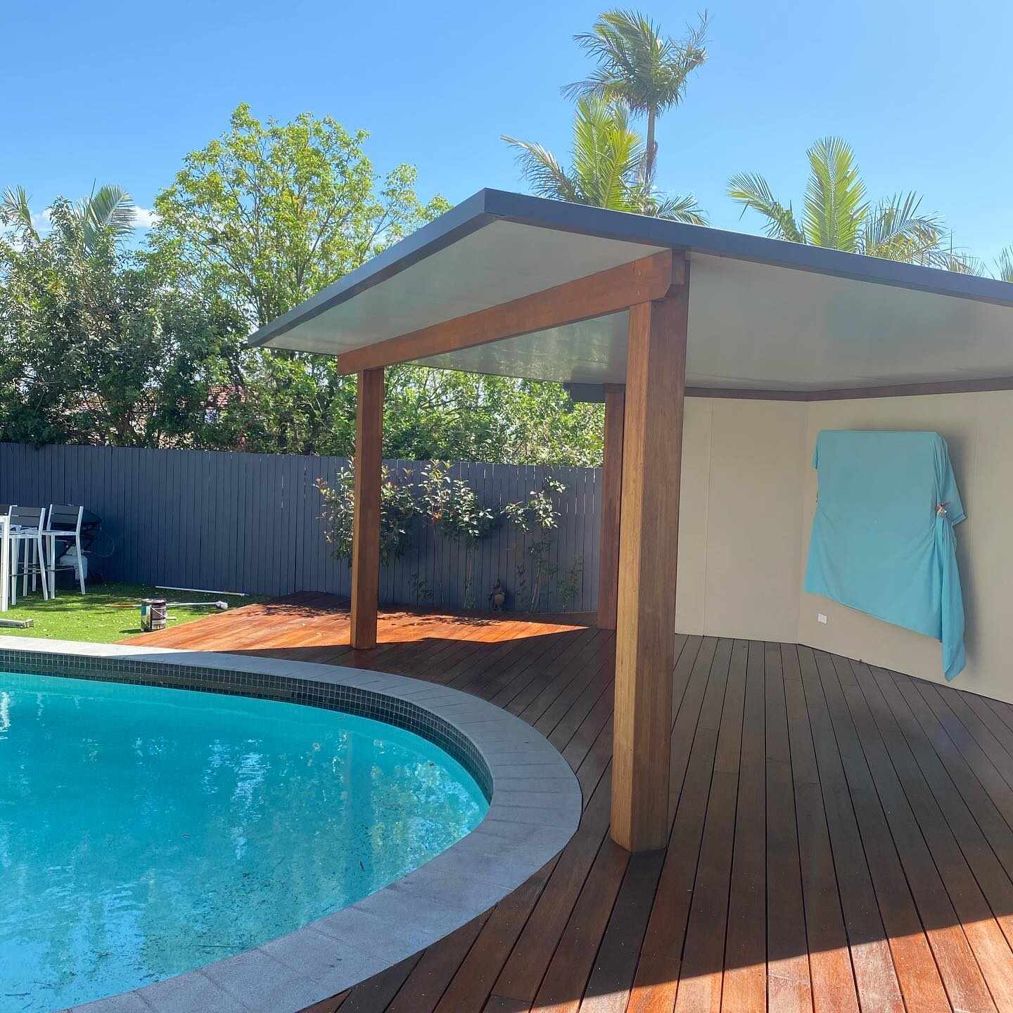 Timber deck around a curved pool under a timber-posted shelter